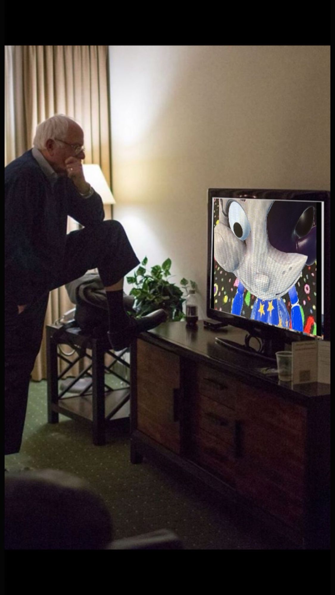 Bernie Sanders looking at a tv. The tv has moon from fnaf on the screen.