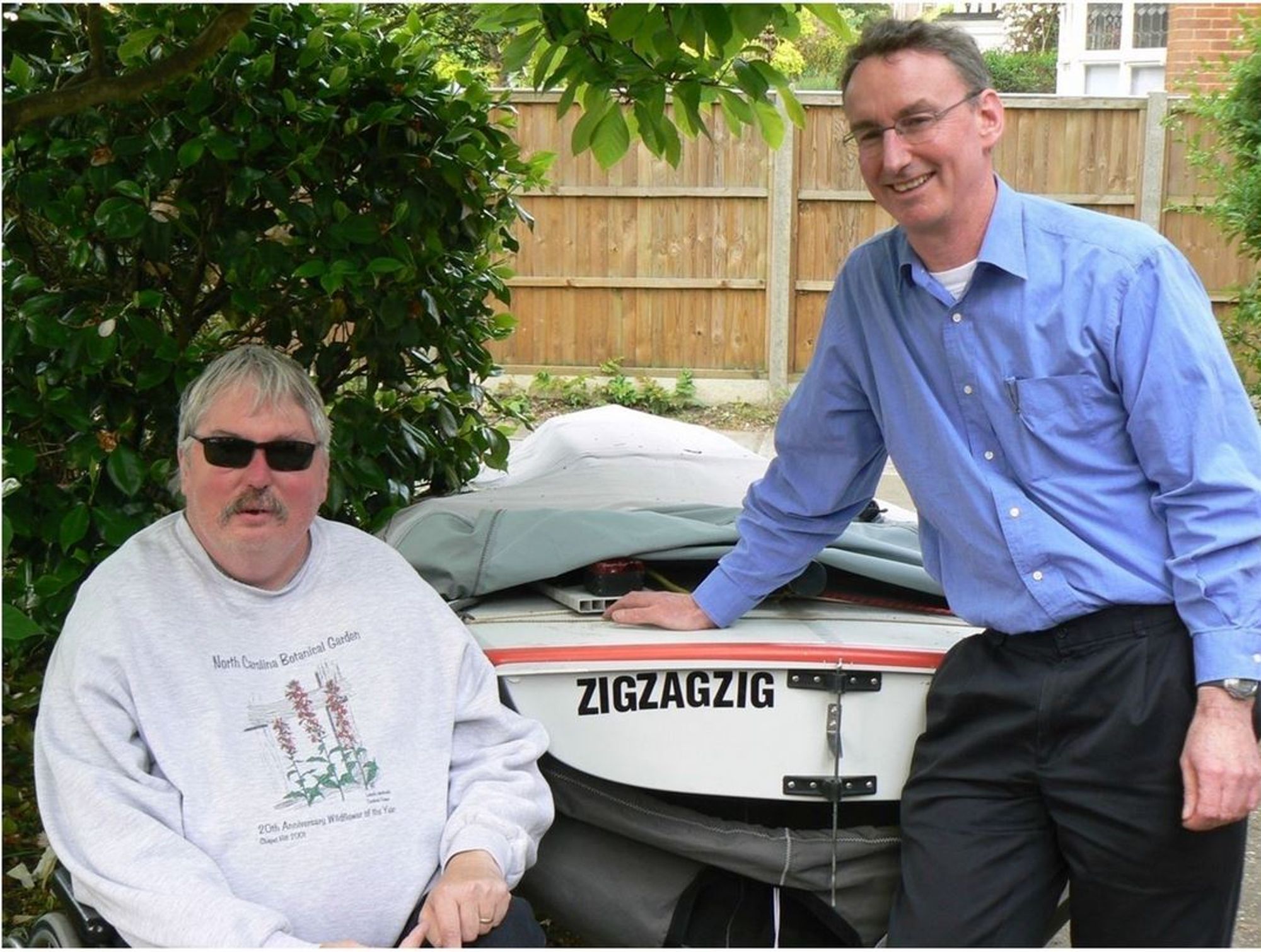 Jeff Dangl and Jonathan Jones in front of a boat named ZIGZAGZIG.