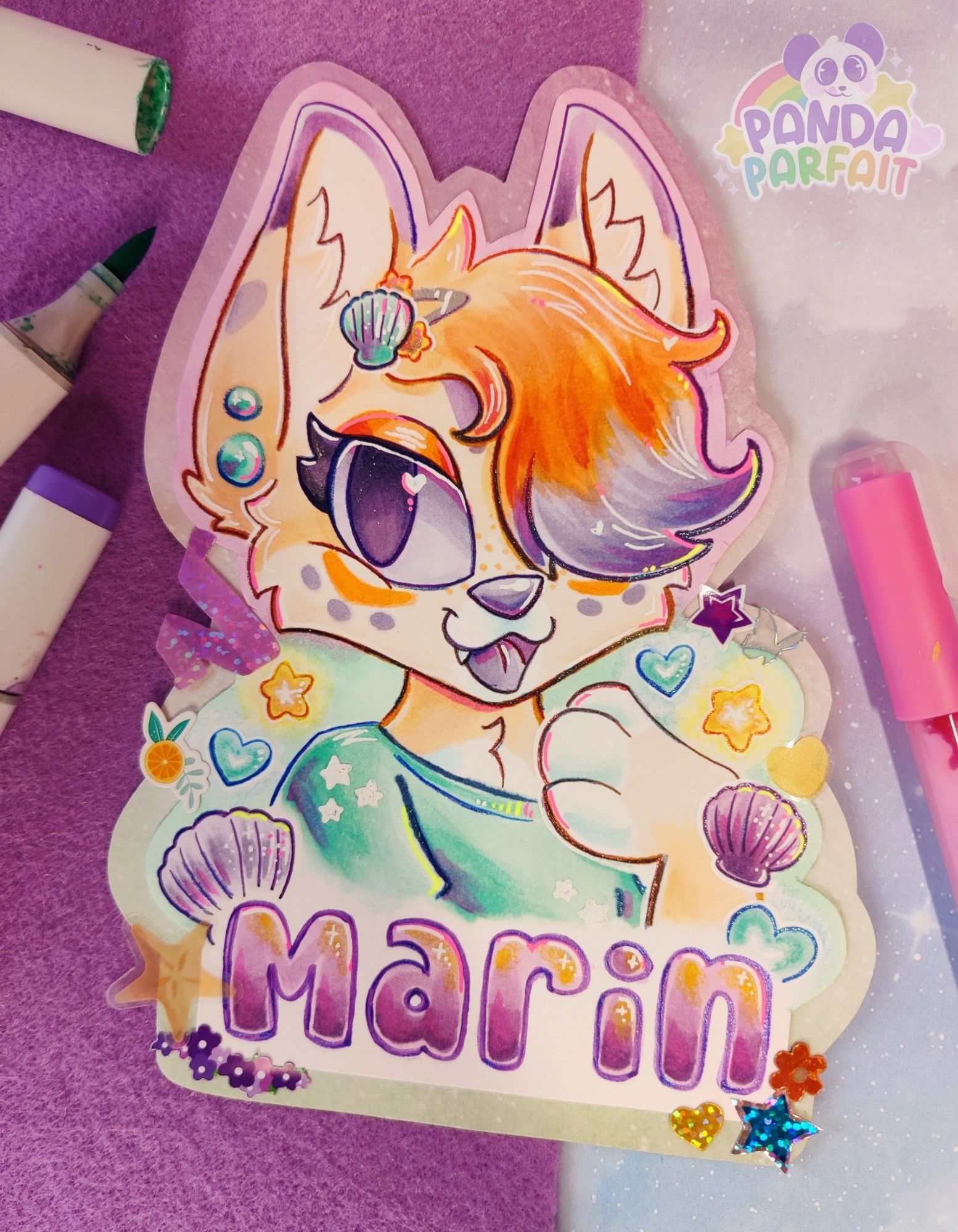 A furry badge done with markers, against a scrapbook paper background