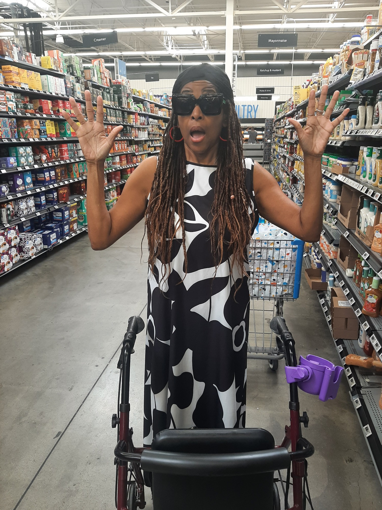 A women shopping in grocery isle with her hands up mimicking a robbery. 