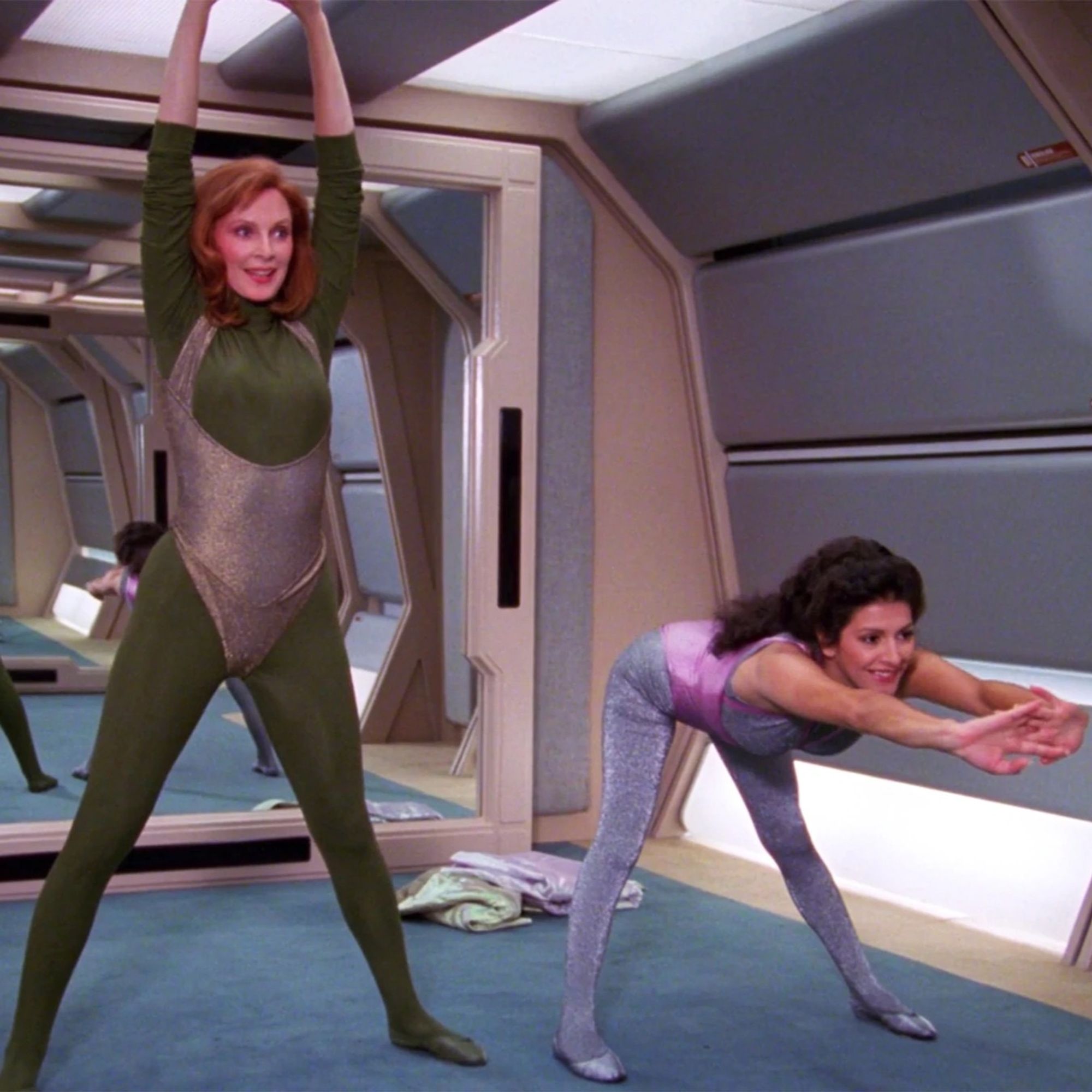 screencap from STAR TREK: THE NEXT GENERATION, beverly and deanna exercise in very 80s spandex, bev in khaki and gold, deanna in lilac and pink.