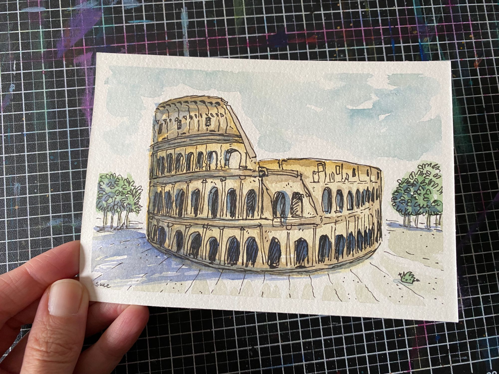 Colosseum mit Tuschestift und Aquarell gezeichnet. Ein Strüppi sitzt daneben.