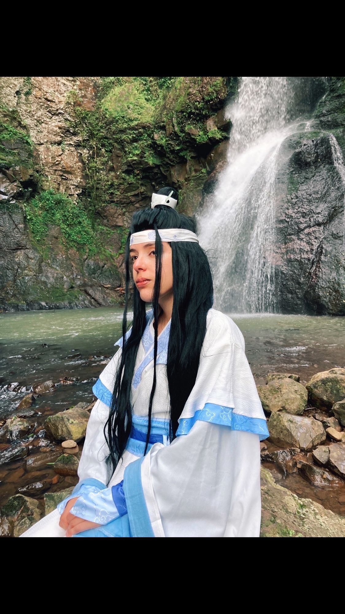 Cosplay of Lan wangji sitting in front of a waterfall