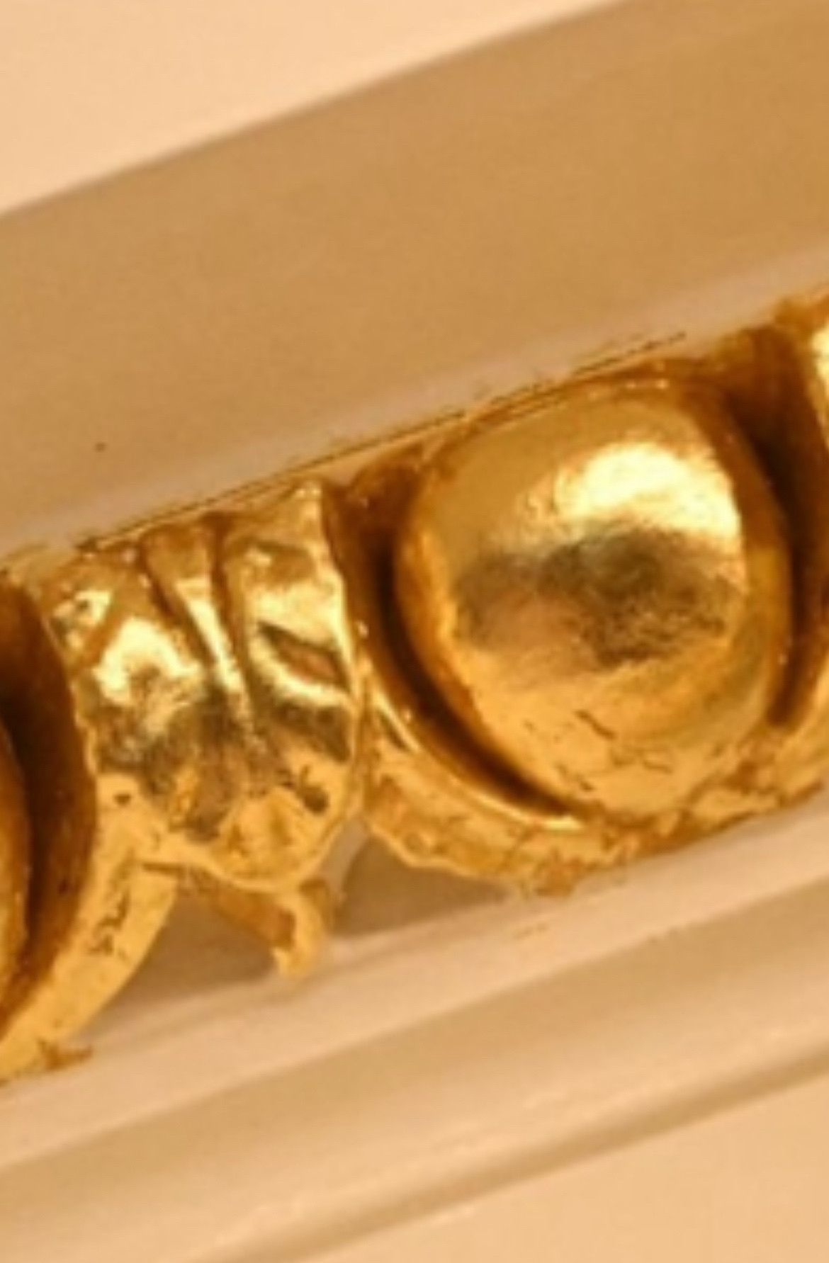 Close up of a moulded wall decoration that has been painted very badly in gold.