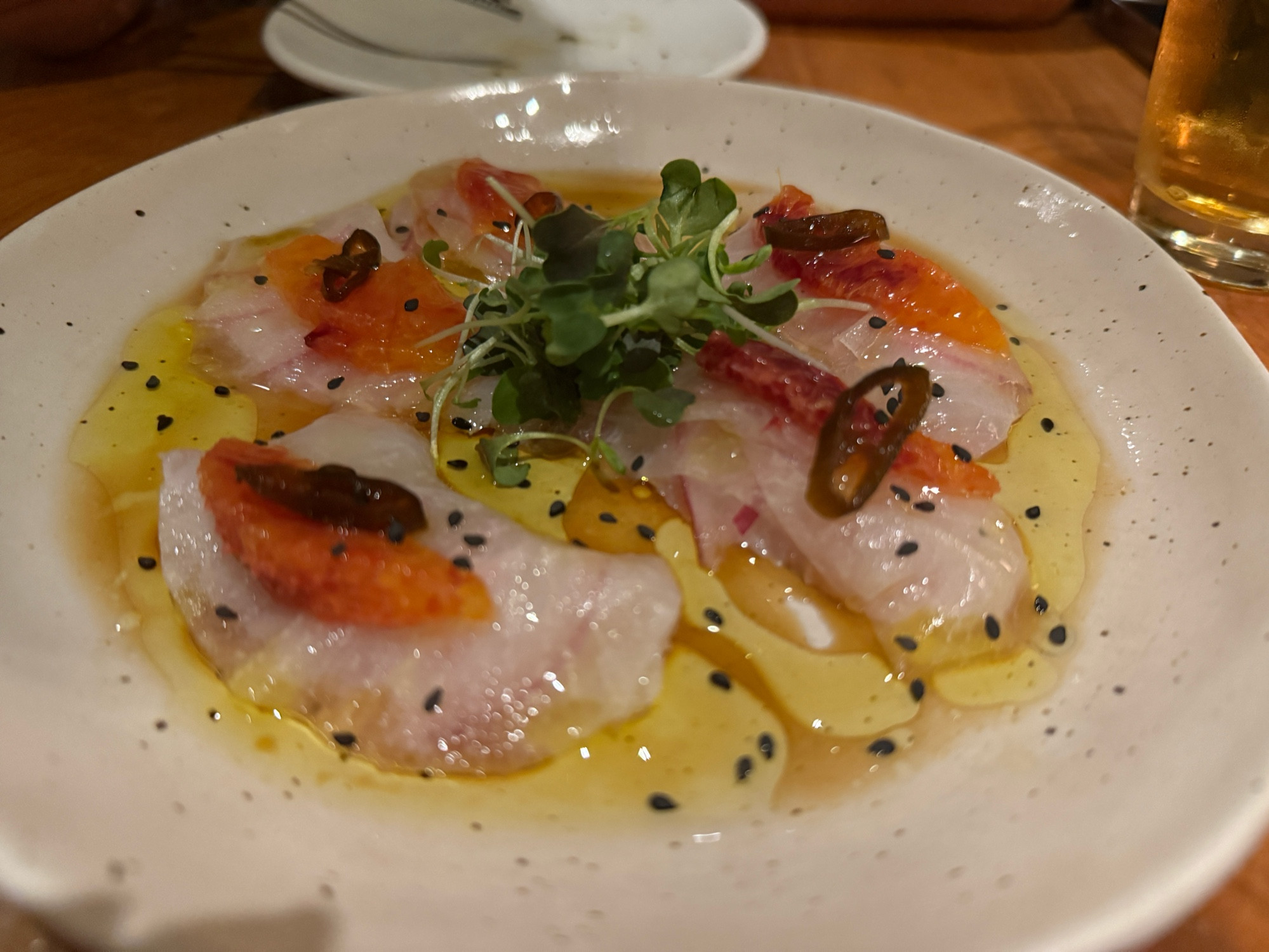 a plate of fluke crudo with blood orange and chili pepper 