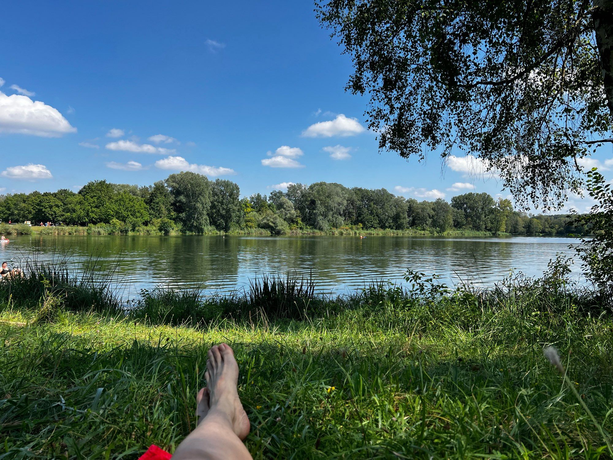 Baggersee Ingolstadt, im Vordergrund meine nackten Füße im Gras.