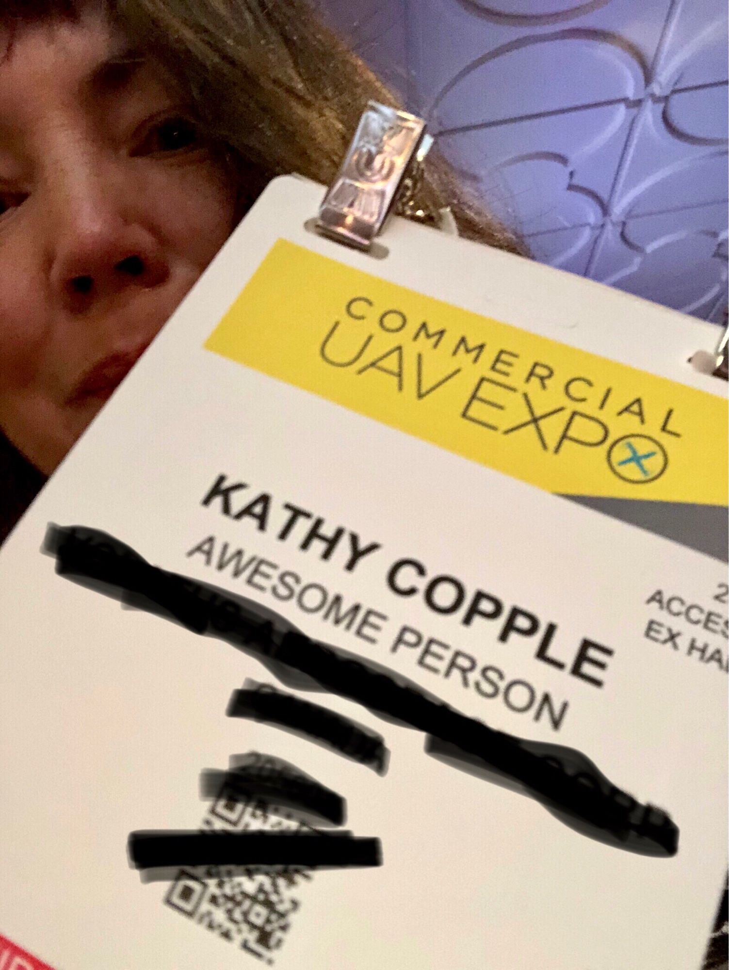 Me peeking around my Commercial UAV Expo entry badge that says “Awesome person” under my name