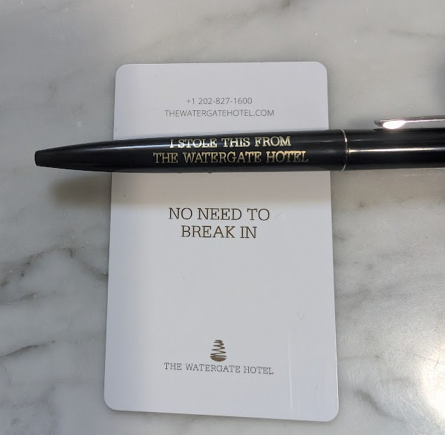 A keycard from the Watergate Hotel saying "No need to break in" and a black ballpoint pen with "I stole this from the Watergate Hotel" written in gold lettering on the pen.