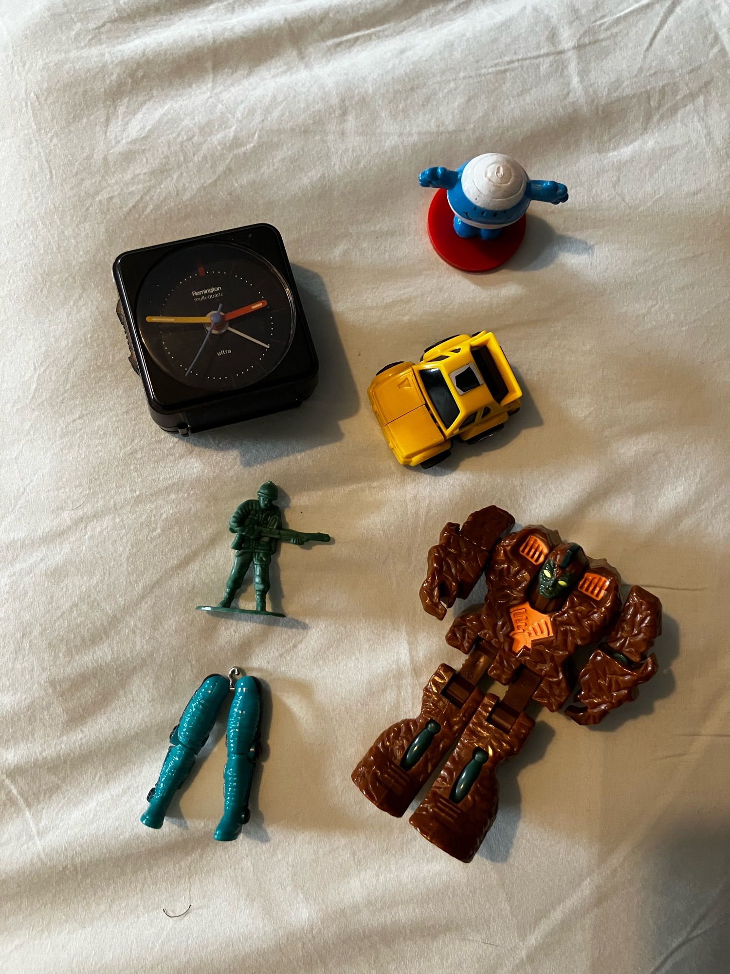 1980s clock, mini autobot, a Rock Lord, Mr Bump stamp, plastic army man, the legs of an Action Force toy.