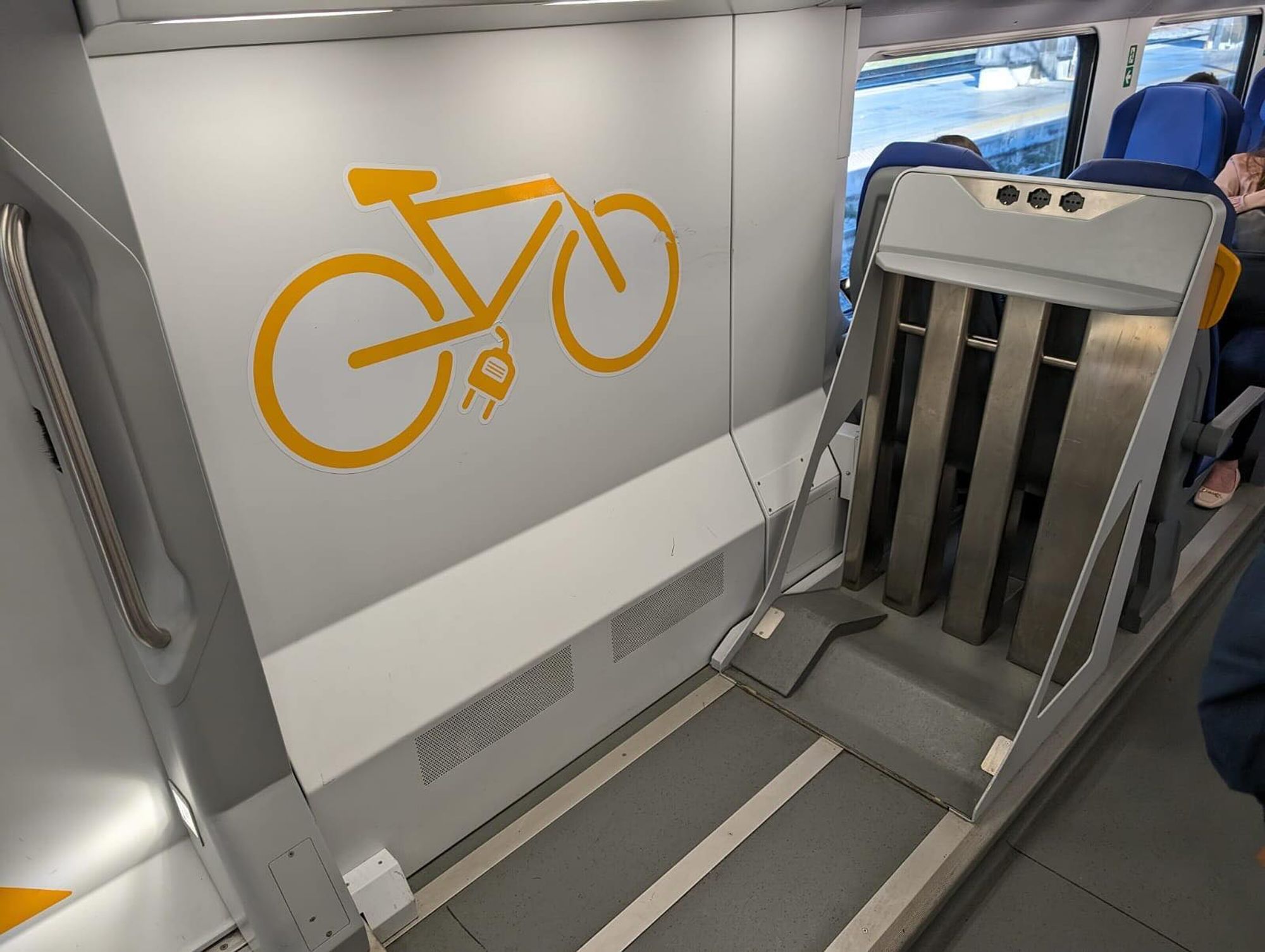 Dockingstation fuer eBikes in einem Zug.... ein eBike Symbol an der Wand. Rechts erste Sitze