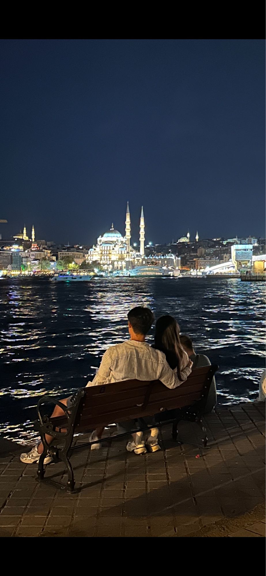 Liebespaar auf einer Bank am Bosporus mit Blick auf beleuchtete Moschee