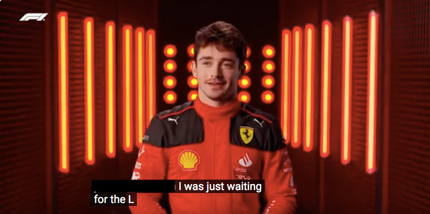 charles leclerc in front of an old f1 pr background. subtitles say "i was just waiting for the L"