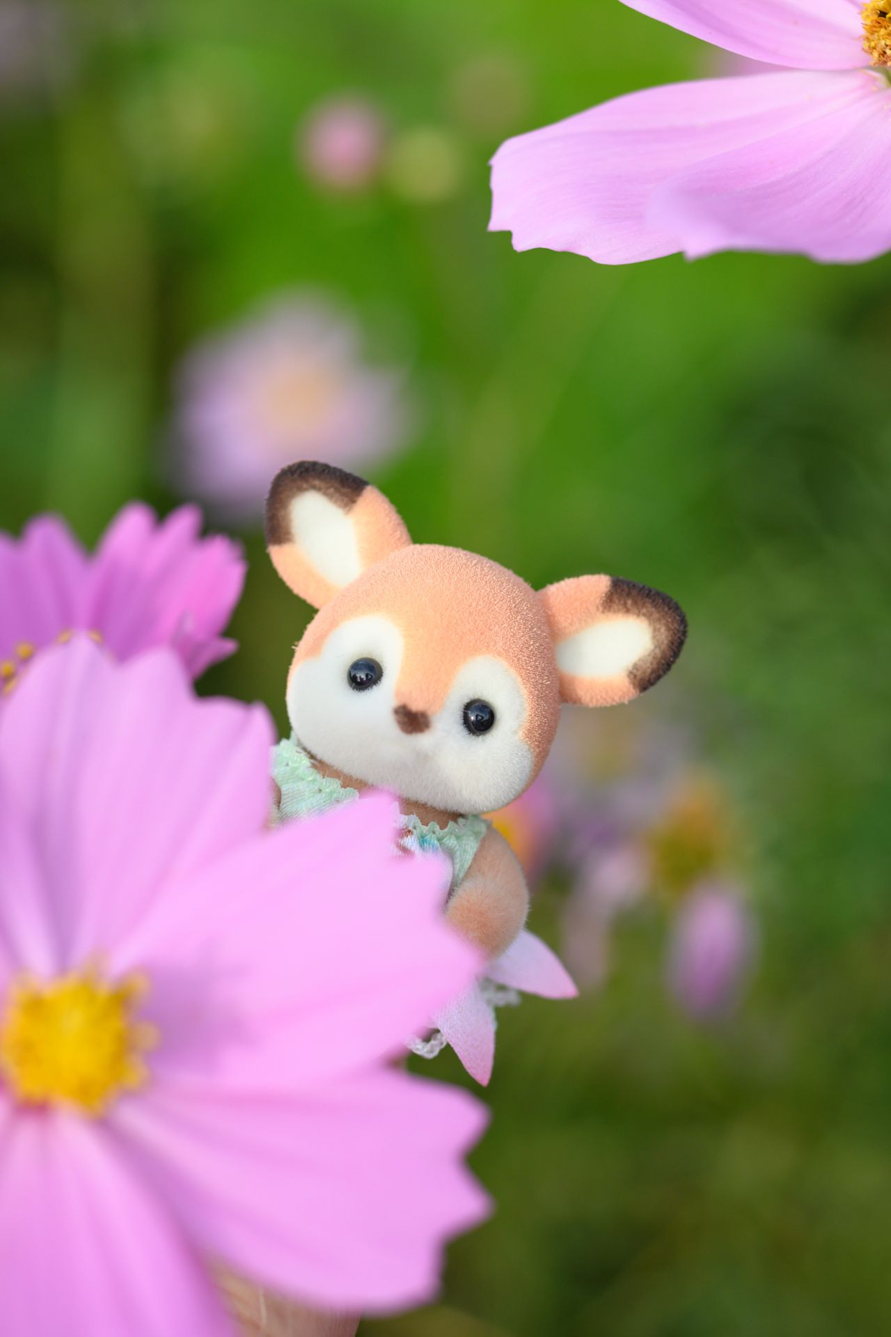 コスモスの花の陰から顔を出すシルバニアファミリーのシカの赤ちゃんの写真