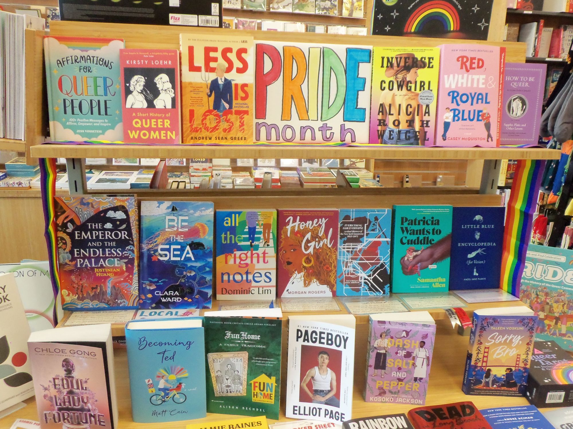 Photo of a Pride Month display of three shelves of 6 to 7 books, including Clara Ward's novel Be the Sea.