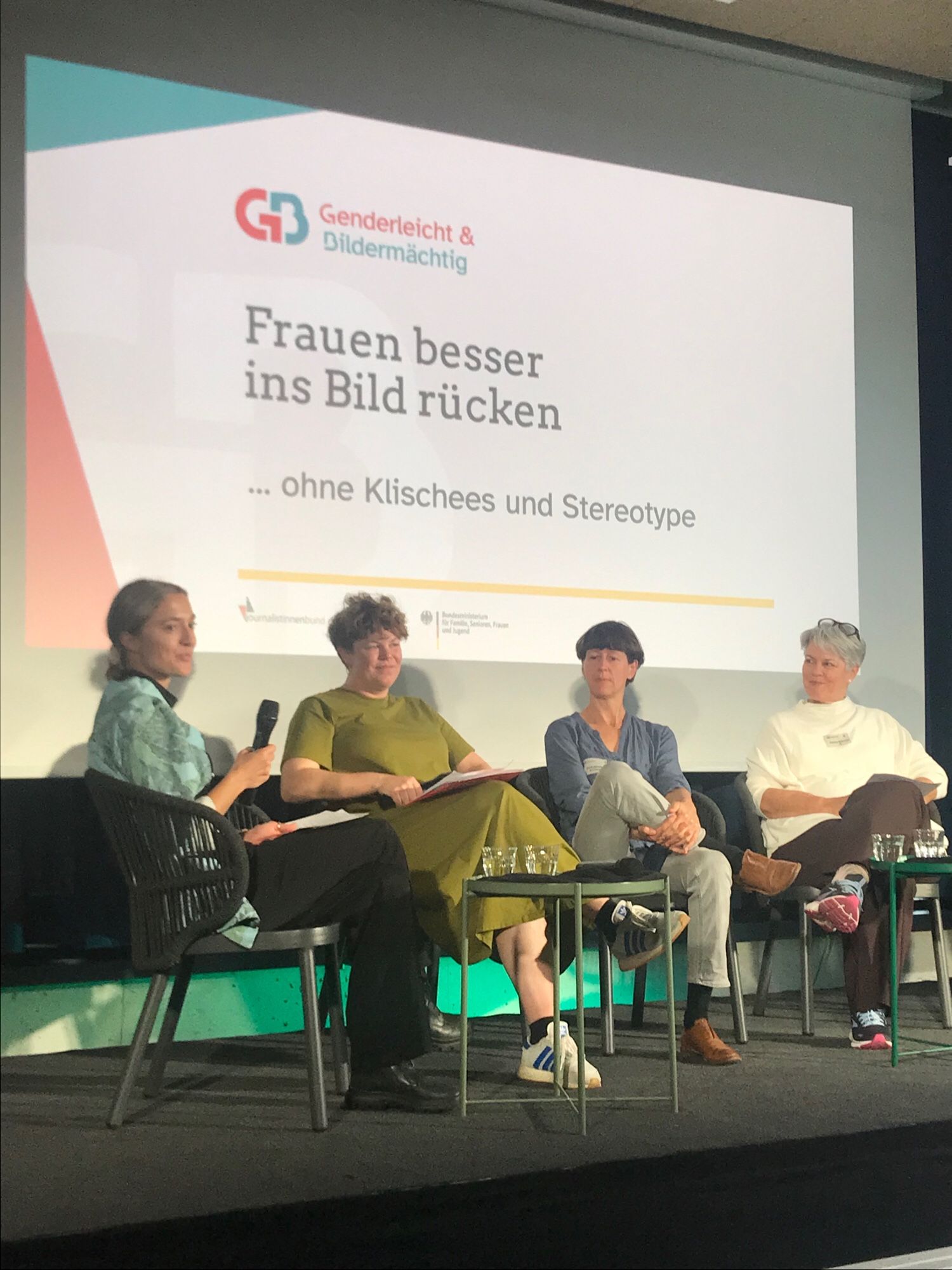 4 Frauen sitzen auf Panel vor Leinwand, darauf Schriftzug Frauen besser ins Bild rücken ohne Klischees und Stereotype