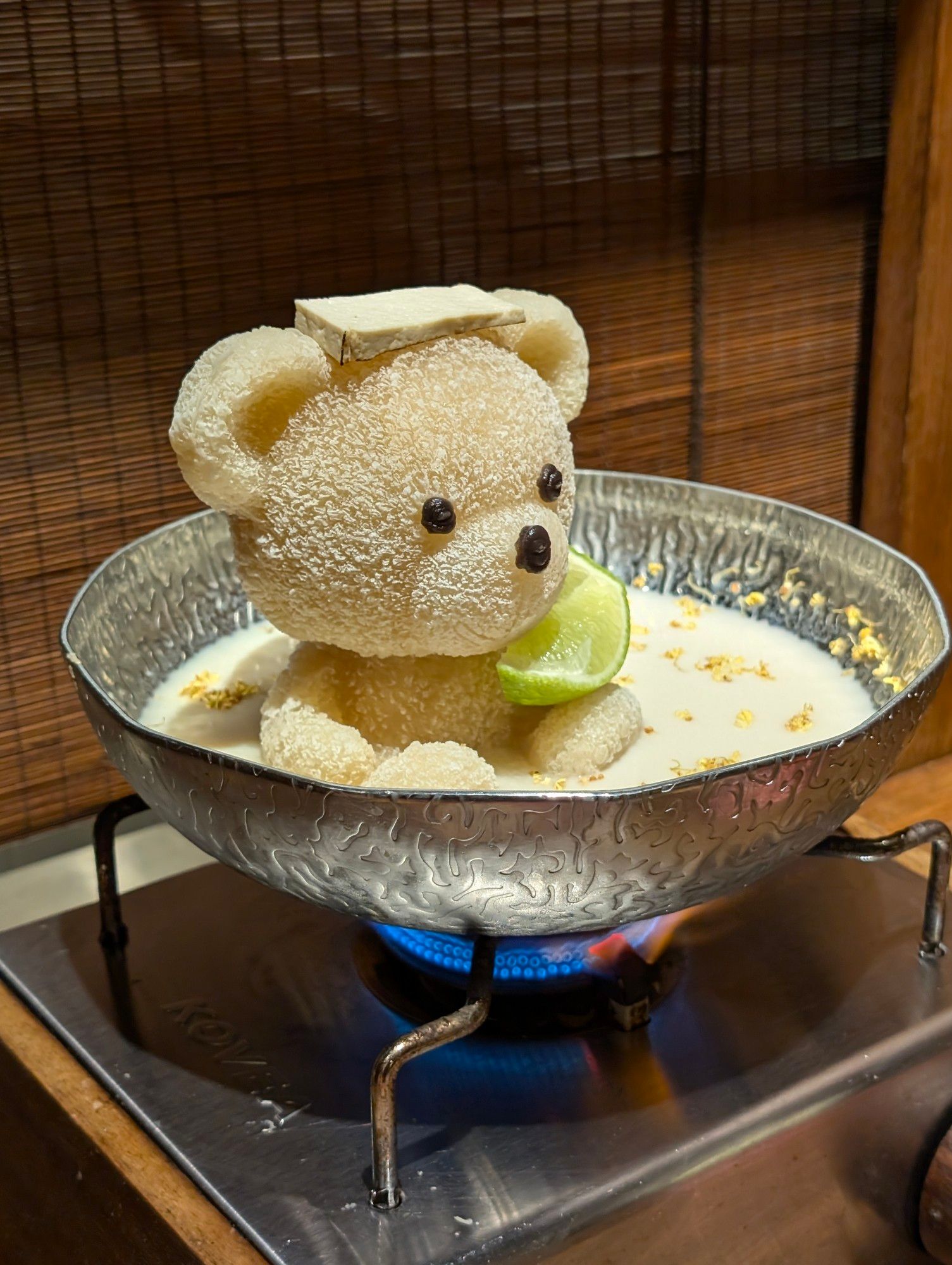 Soy bean hot pot with a teddy bear in it. The hot pot has been placed onto a lit gas stove