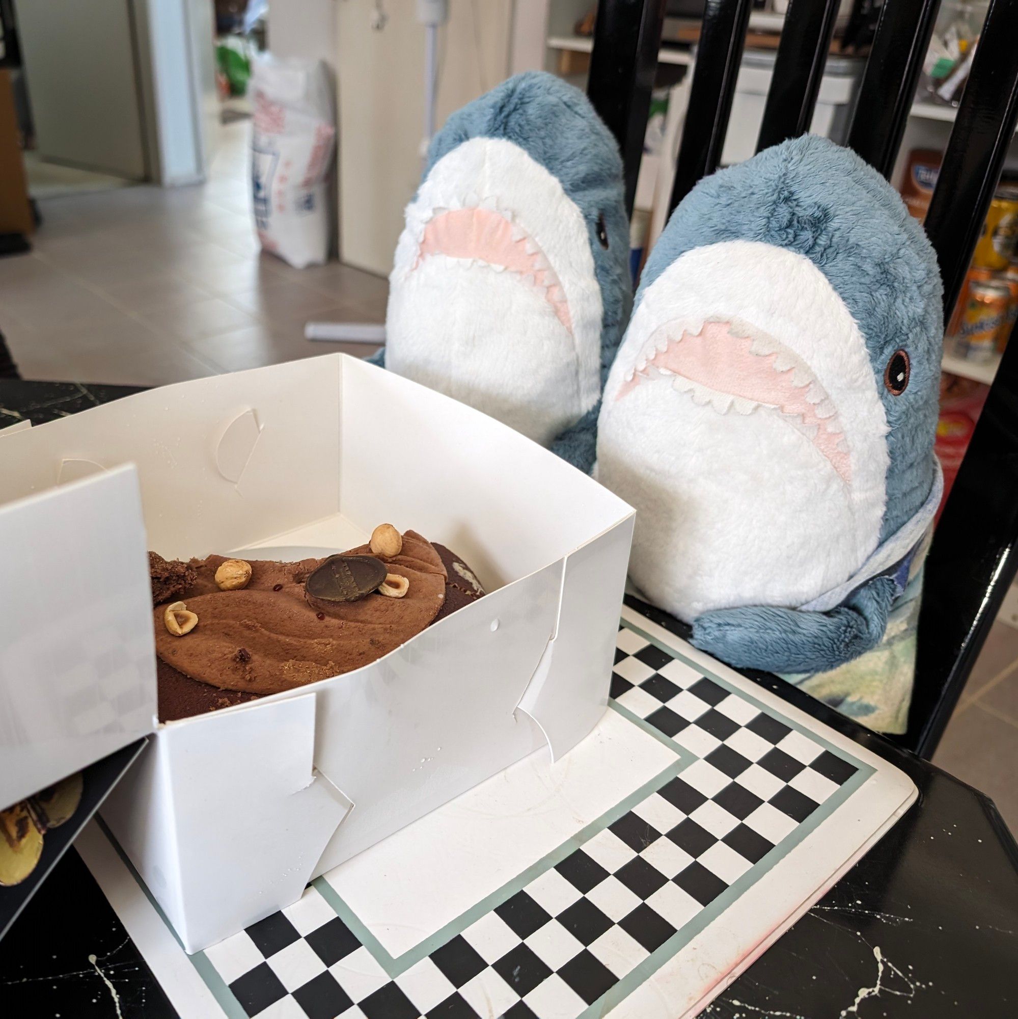 Two small IKEA sharks sitting at a table with an ice cream cake