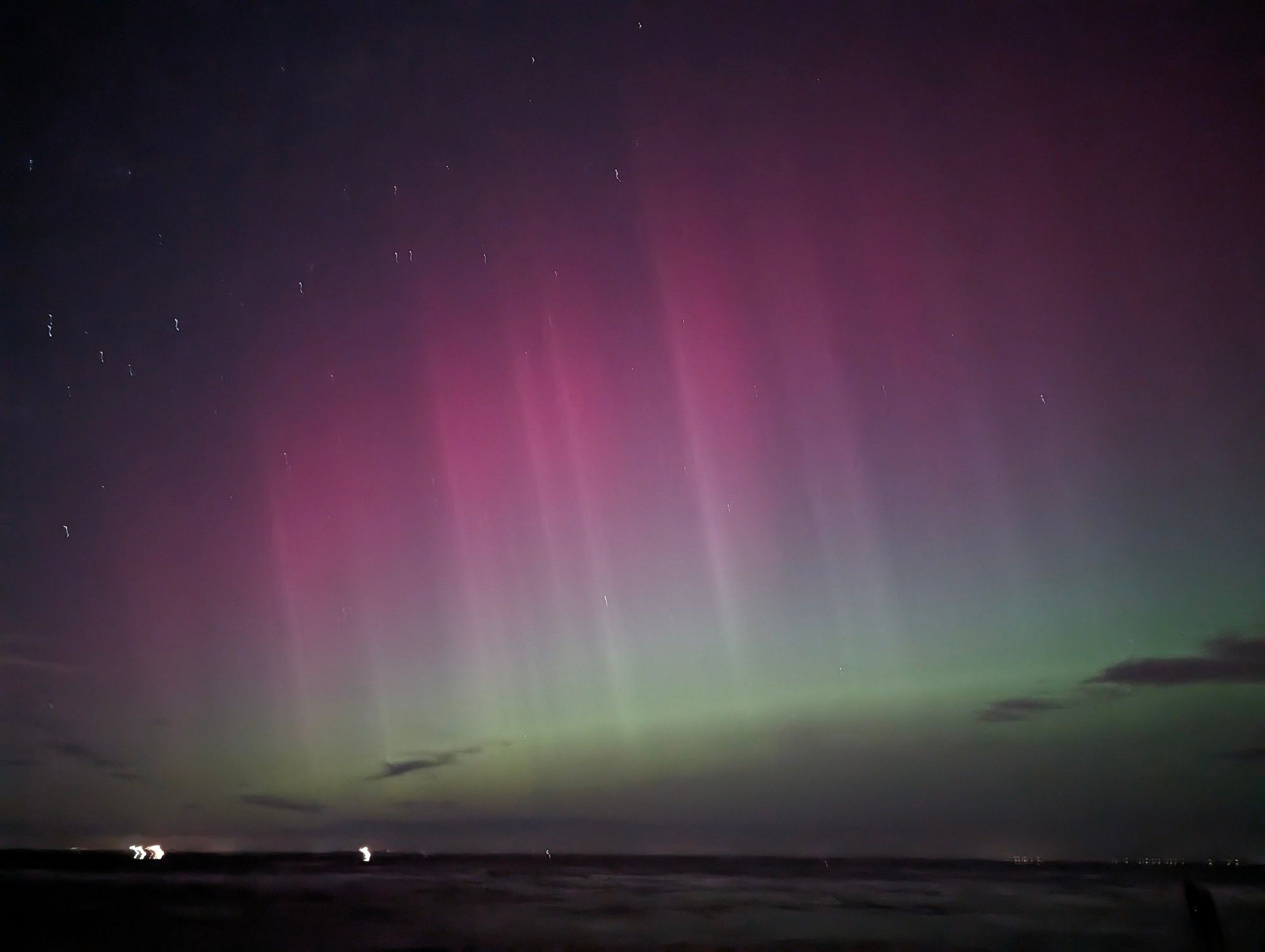 A pink and green aurora with pillars of light