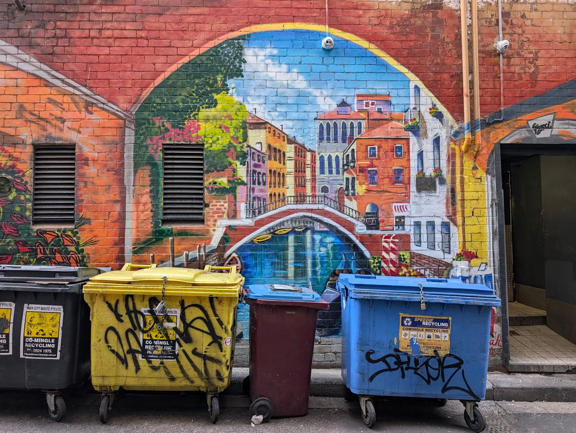 Mural in Mornane Place depicting a canal and a bridge surrounded by colourful houses