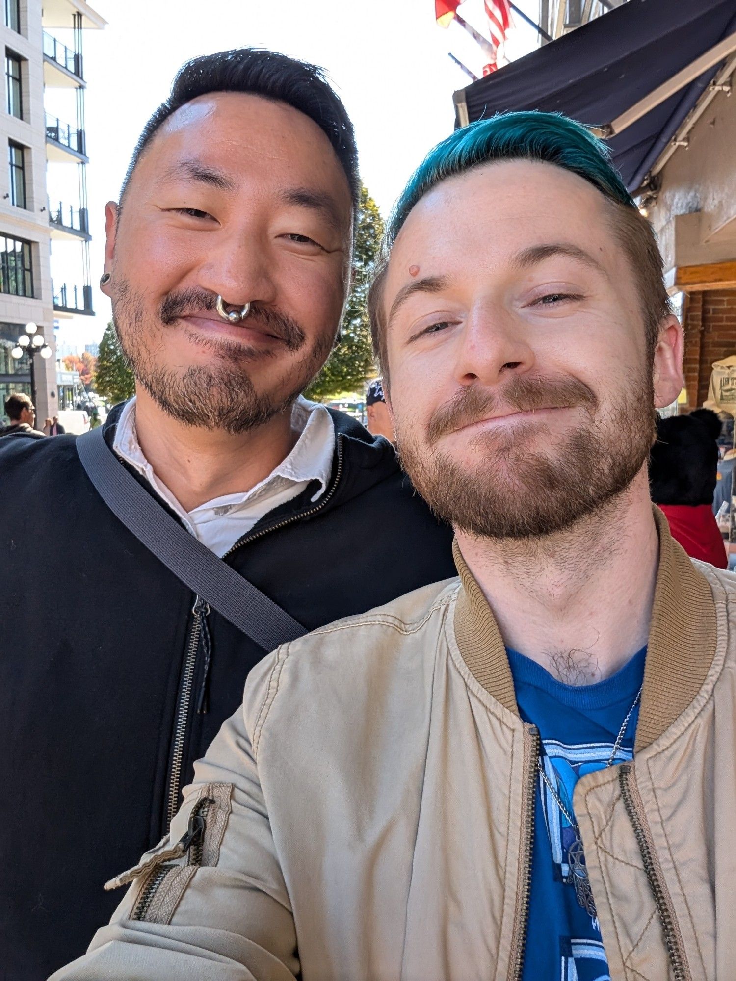 Two men standing on the side of a downtown street corner.