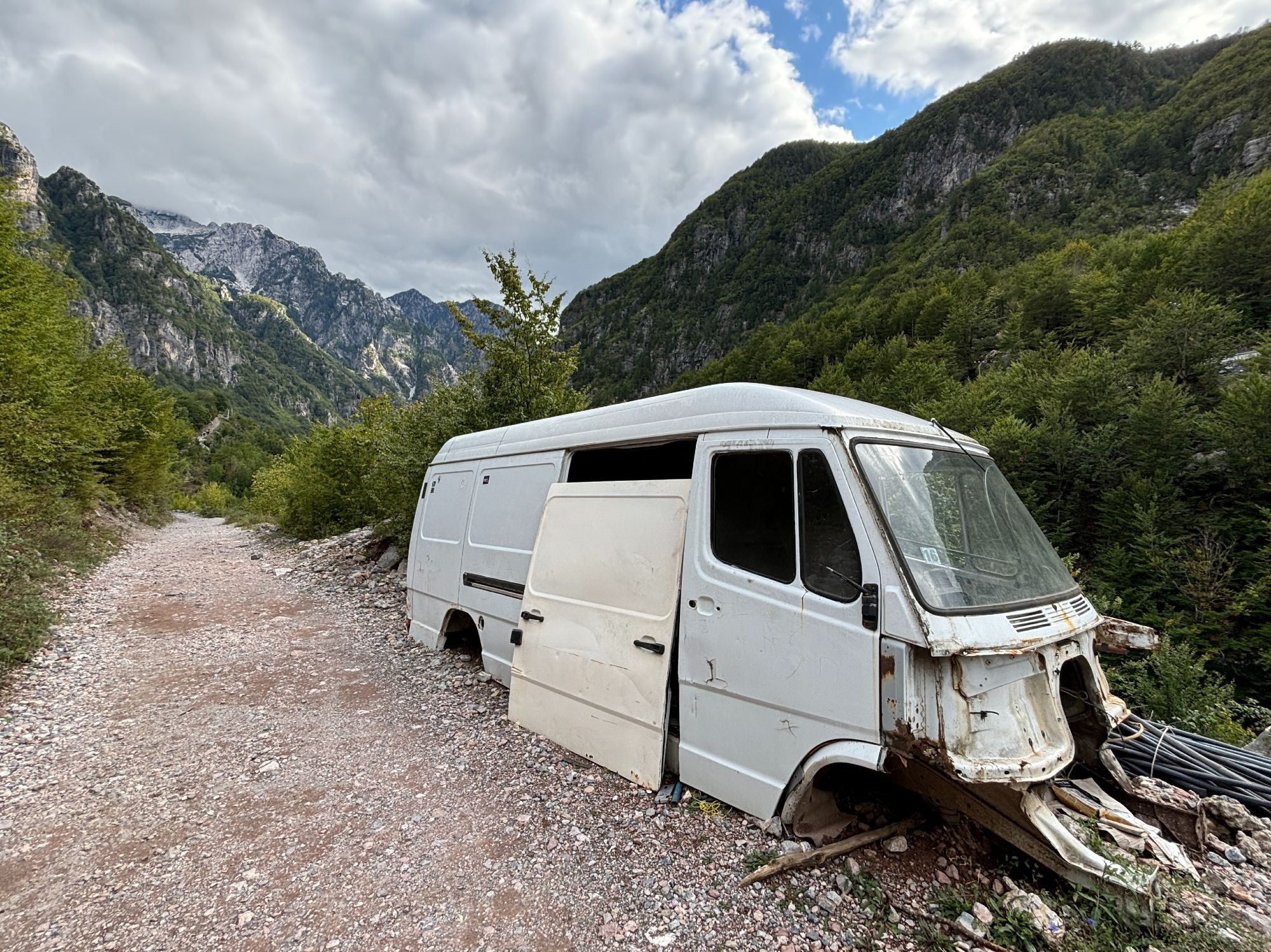 The bodywork of a 1980s Mercedes-Benz van, minus its chassis and drivetrain, sitting at the side of a mountain track near Theth in Albania