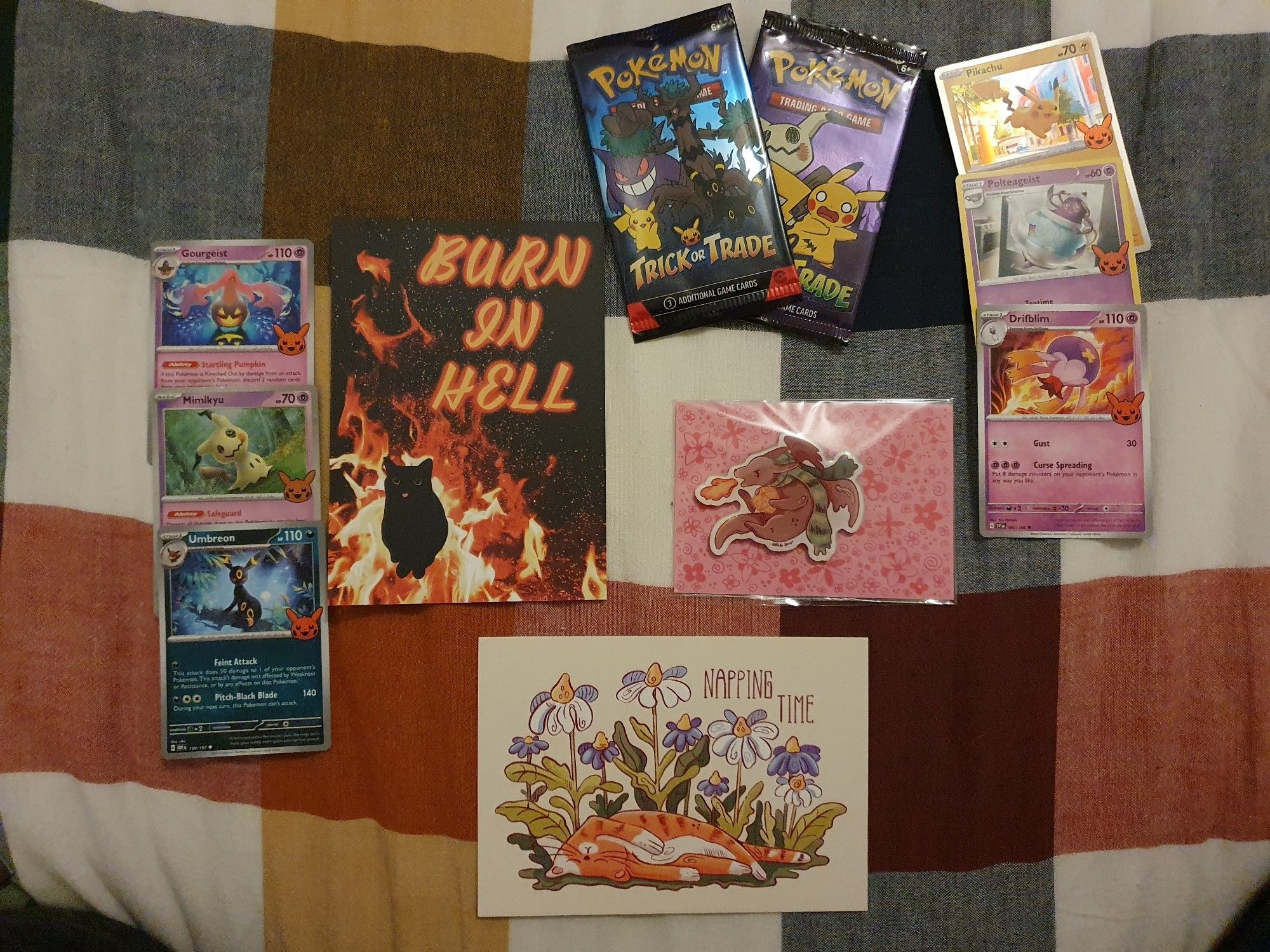 two cat postcards framed by pokemon cards of the halloween special edition (also the packaging of the bosters) and a tiny dragon magnet