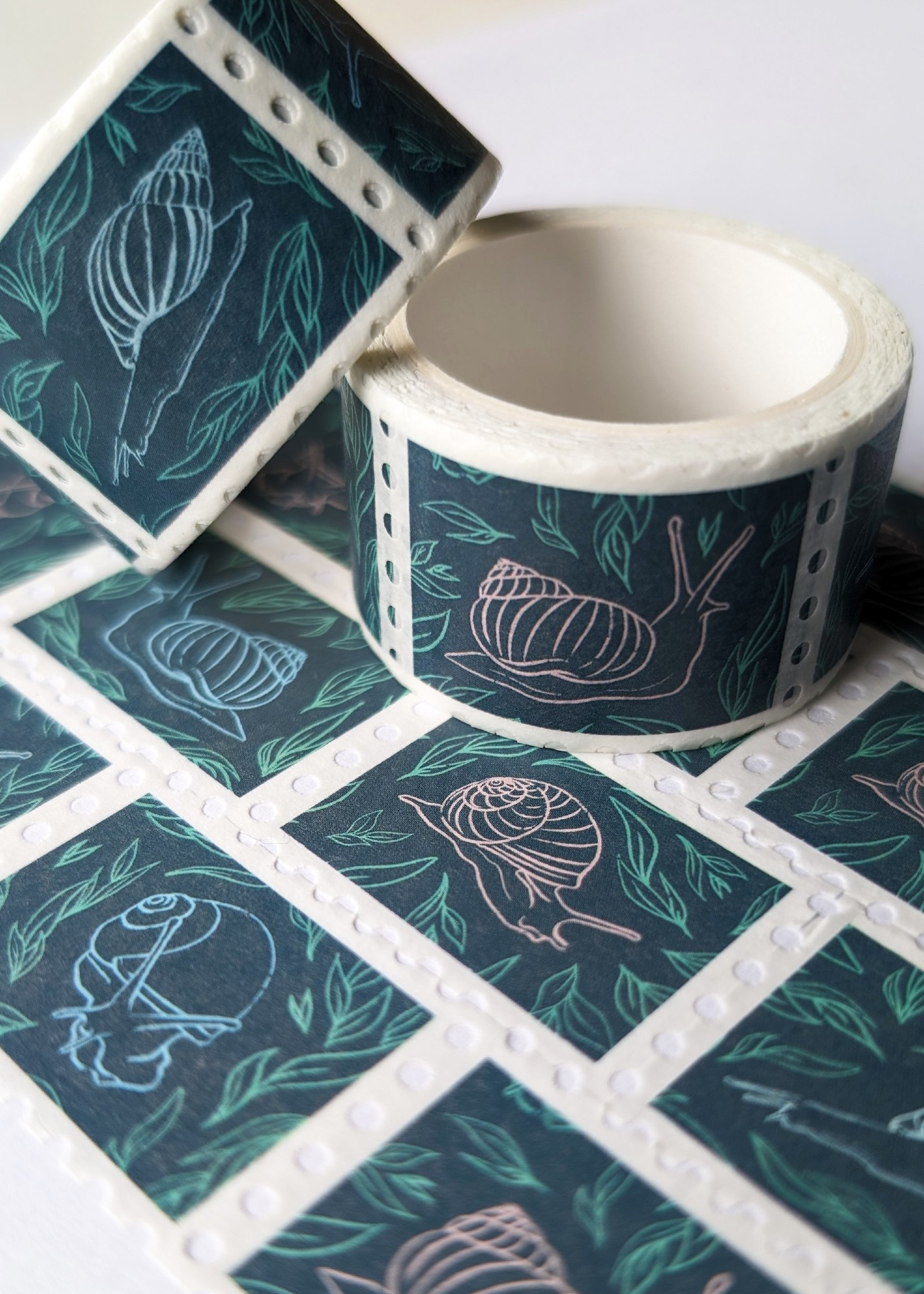 A photograph of some rolls of washi tape with snail illustrations on them.