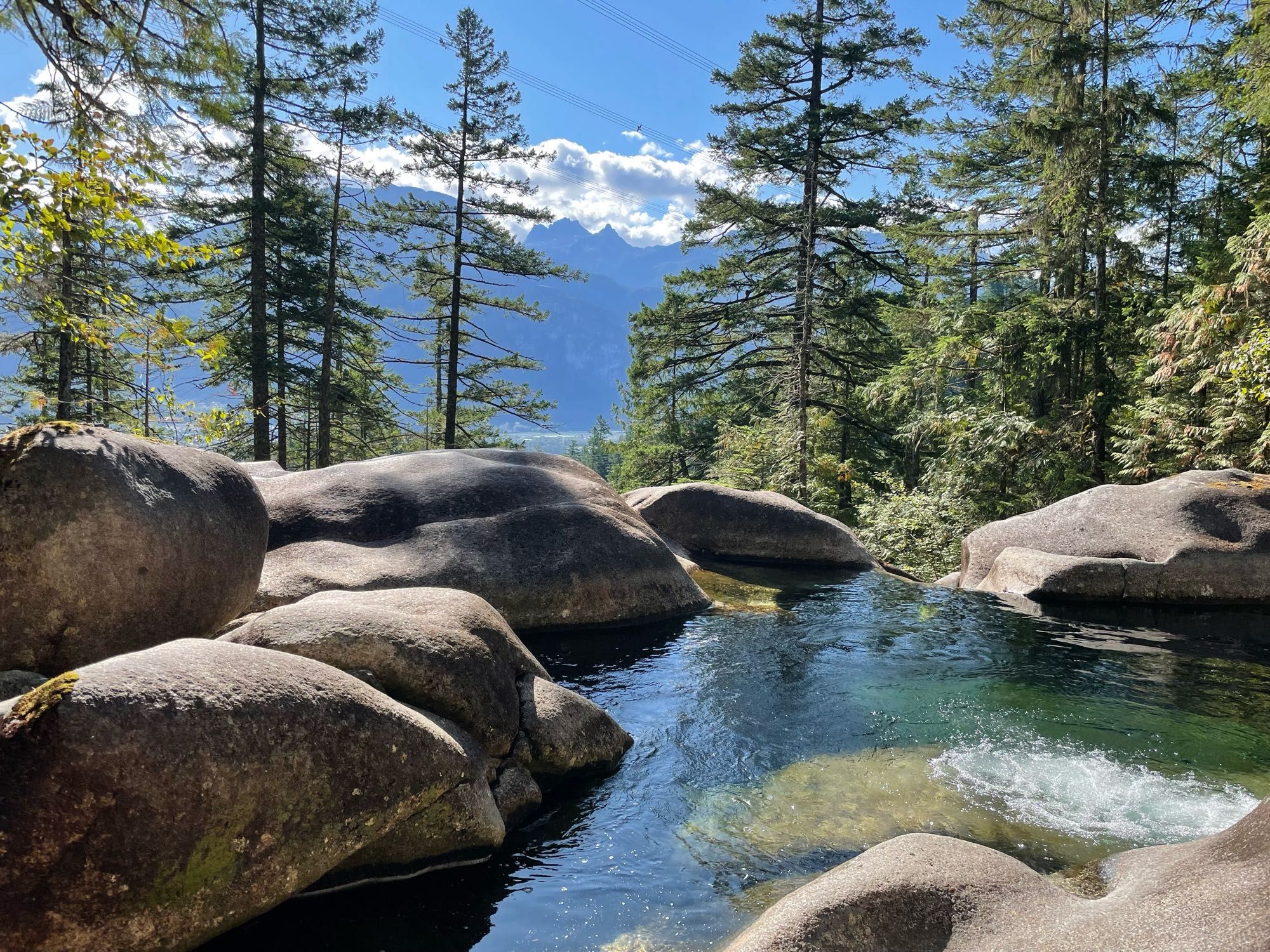 This is a wonderful little waterfall pool overlooking Squamish. Waterworn boulders surround the pool, and the “Sea to Sky” valley is in the background.