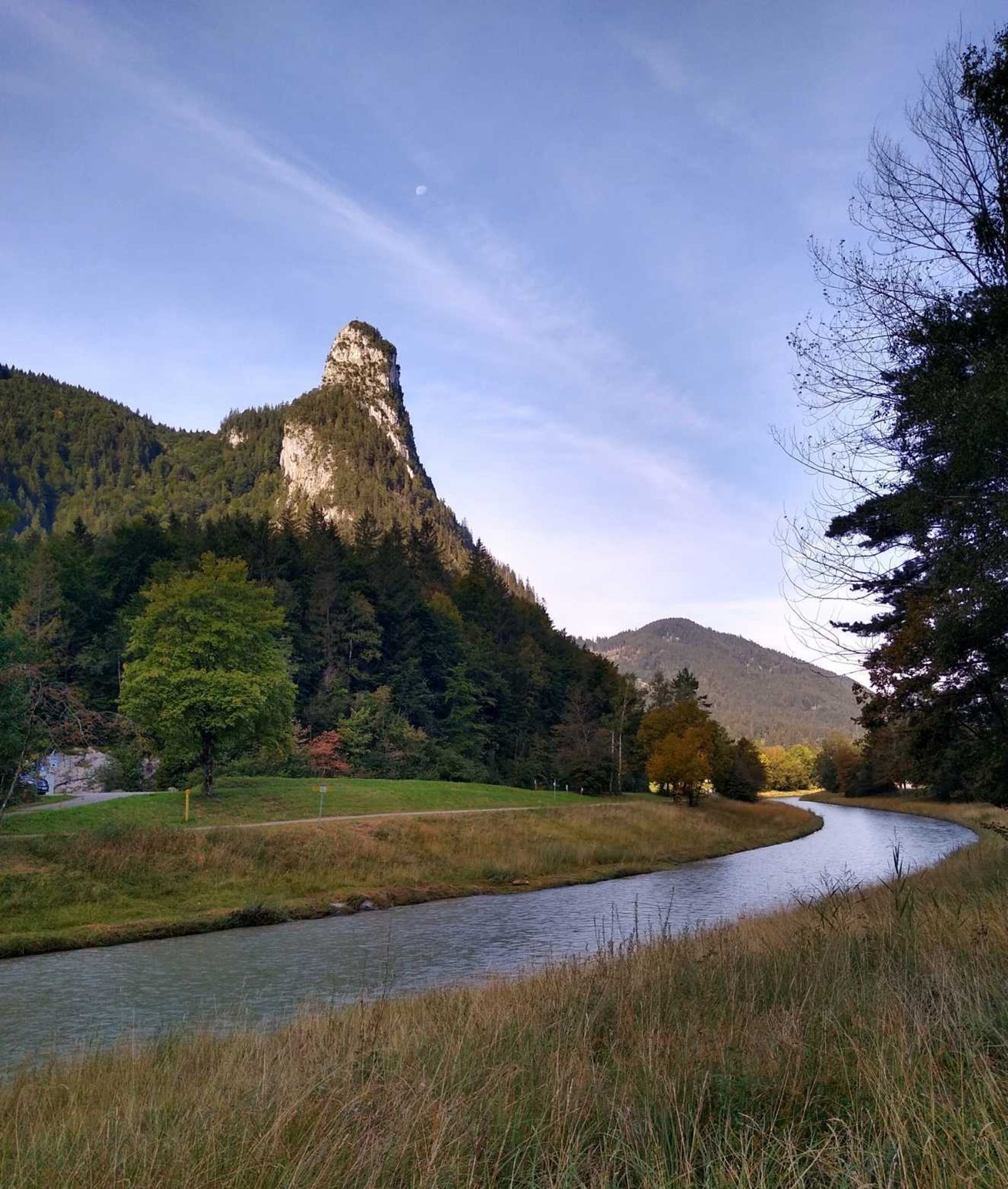 Ein schroffer Gipfel, davor fließt die Ammer in einem Bogen herum, rechts am Bildrand ein Baum