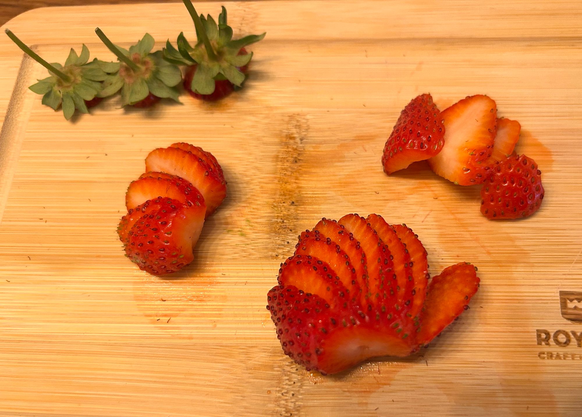 Strawberries fanned out in thin slices on a cutting board.