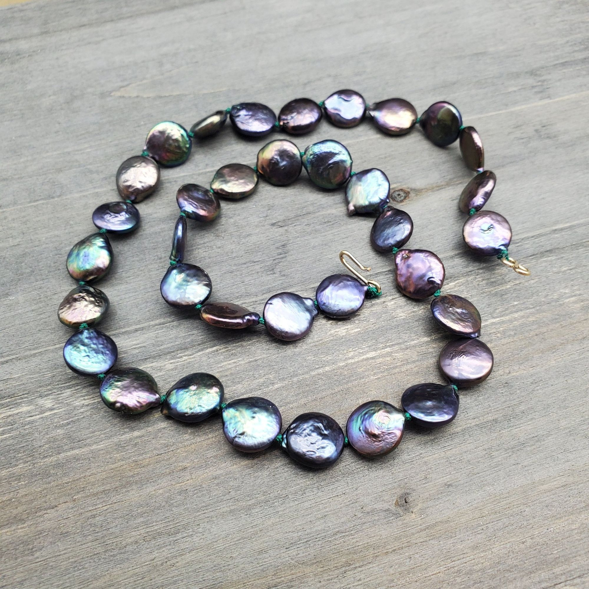 a handstrung strand of coin pearls in dark rainbow colors