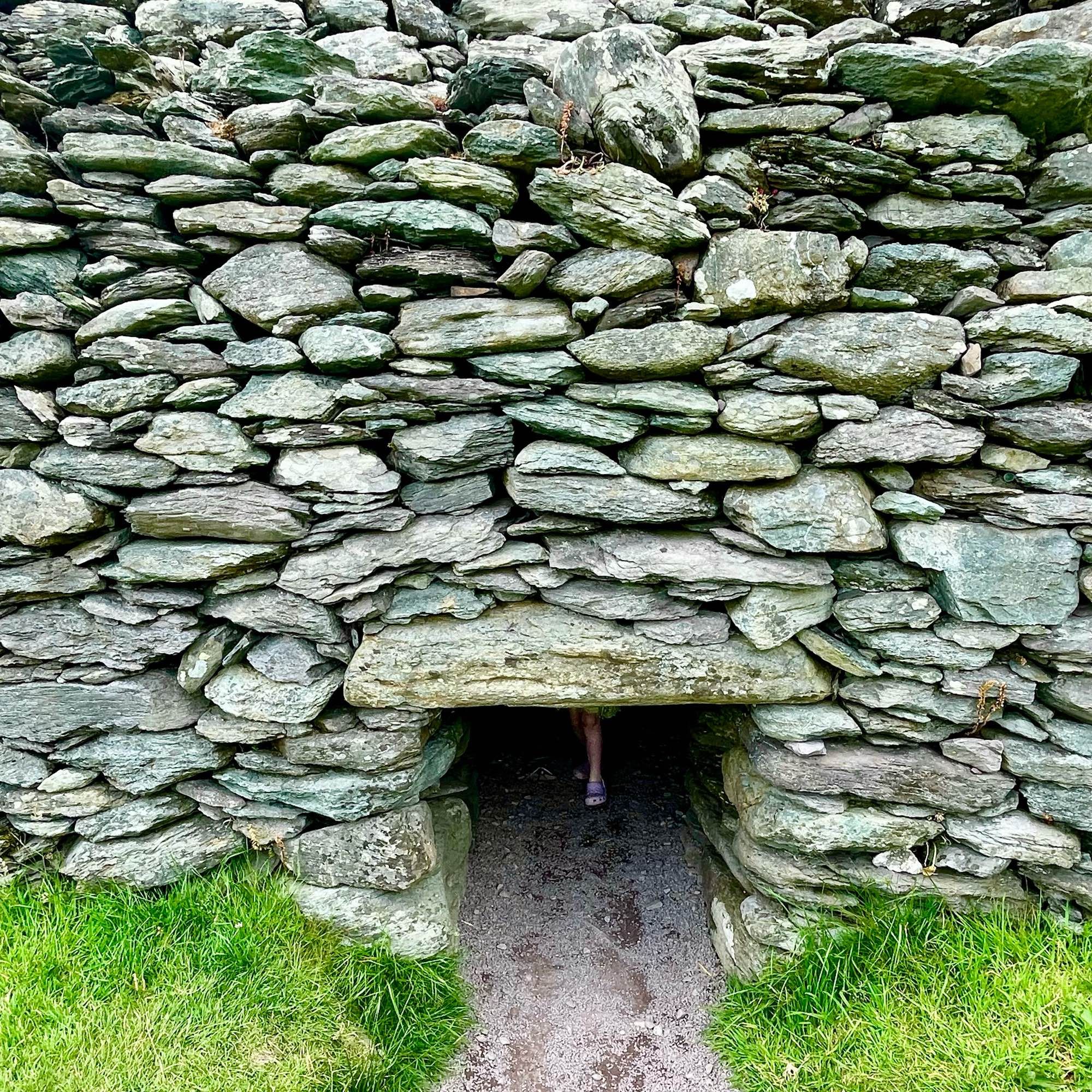 Stone structure with a small, narrow entrance partially obscured by a child standing inside.