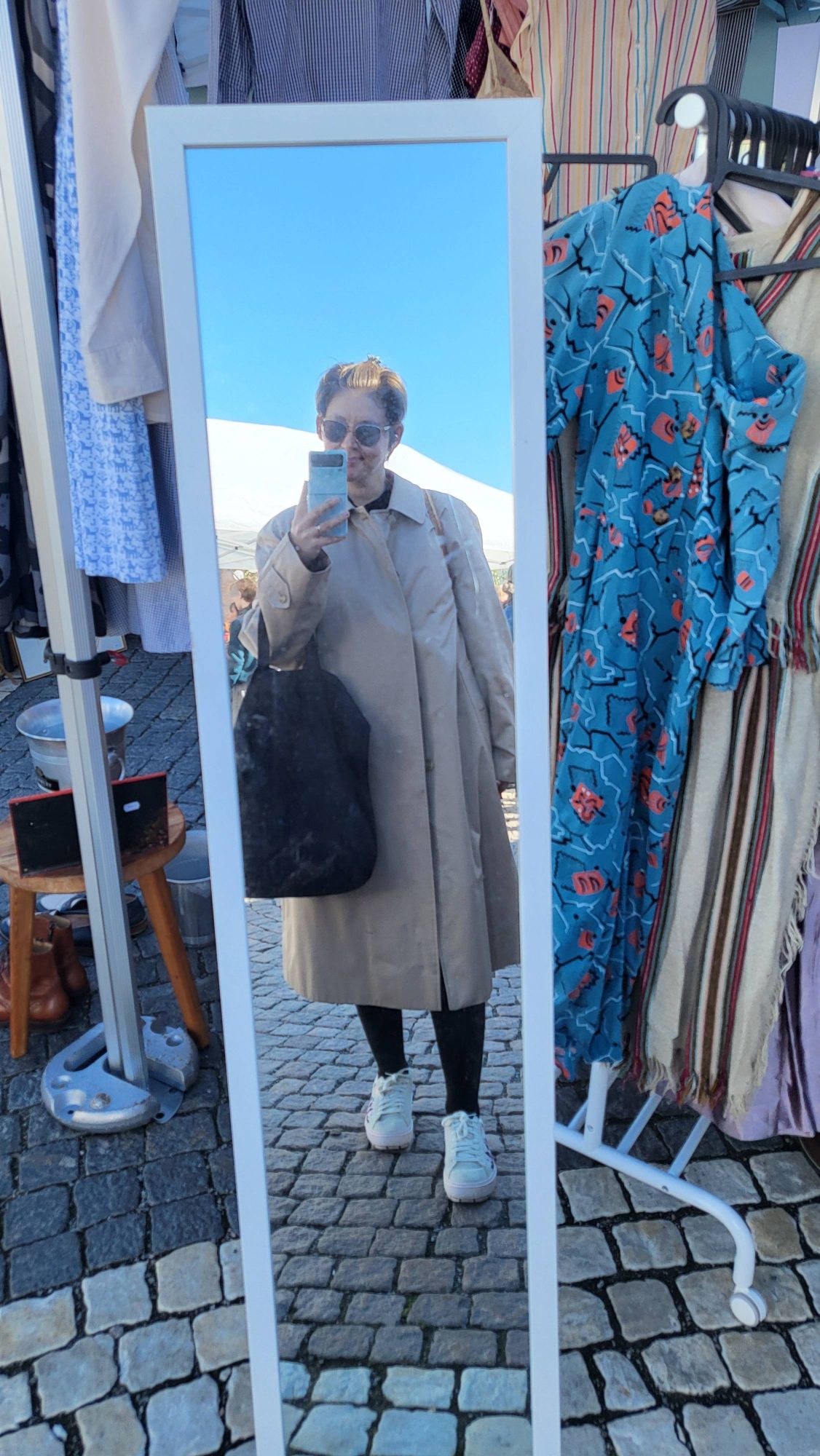 Kvinna i oversize trenchcoat i en spegel.