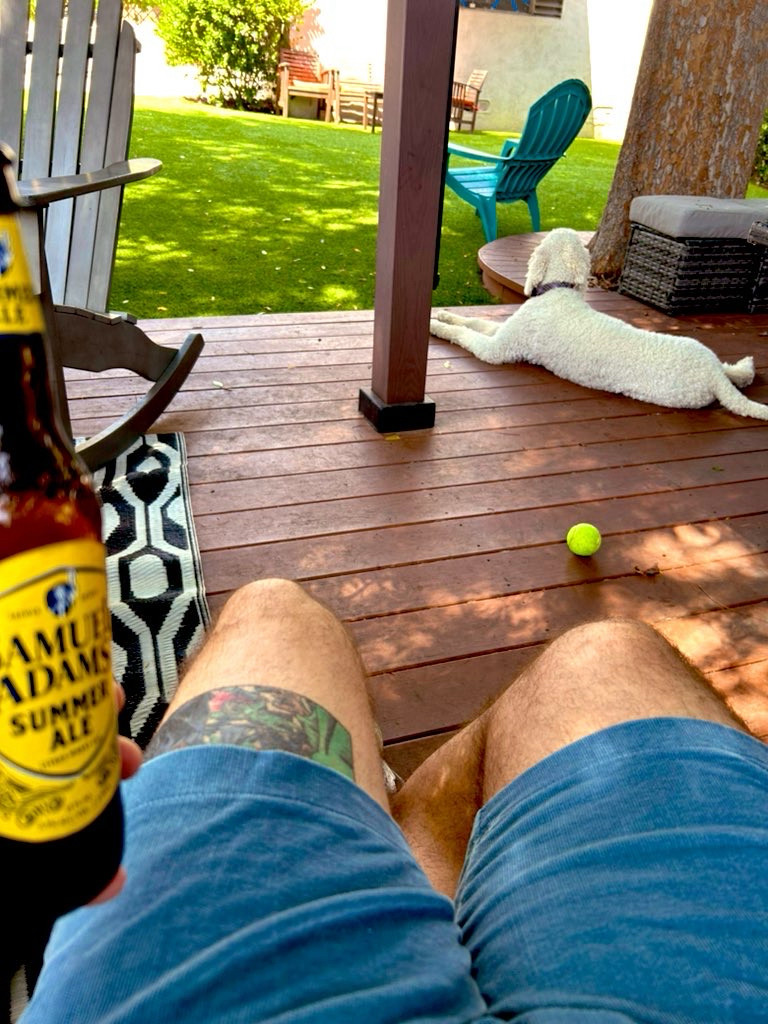 Sitting on my deck, holding a beer while my dog sits nearby