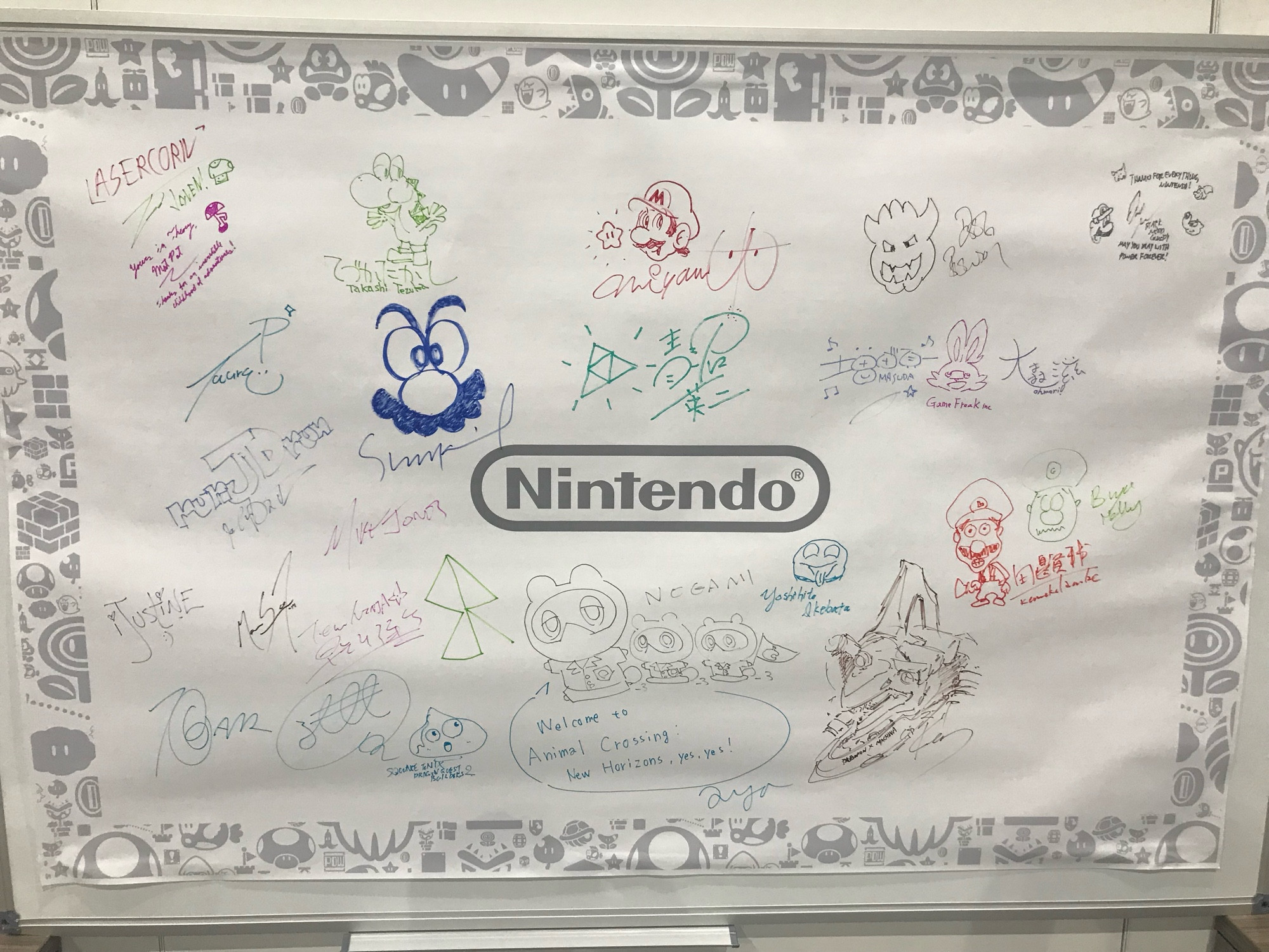 Nintendo branded poster with the racetrack logo in the middle and signatures of developers and staff.