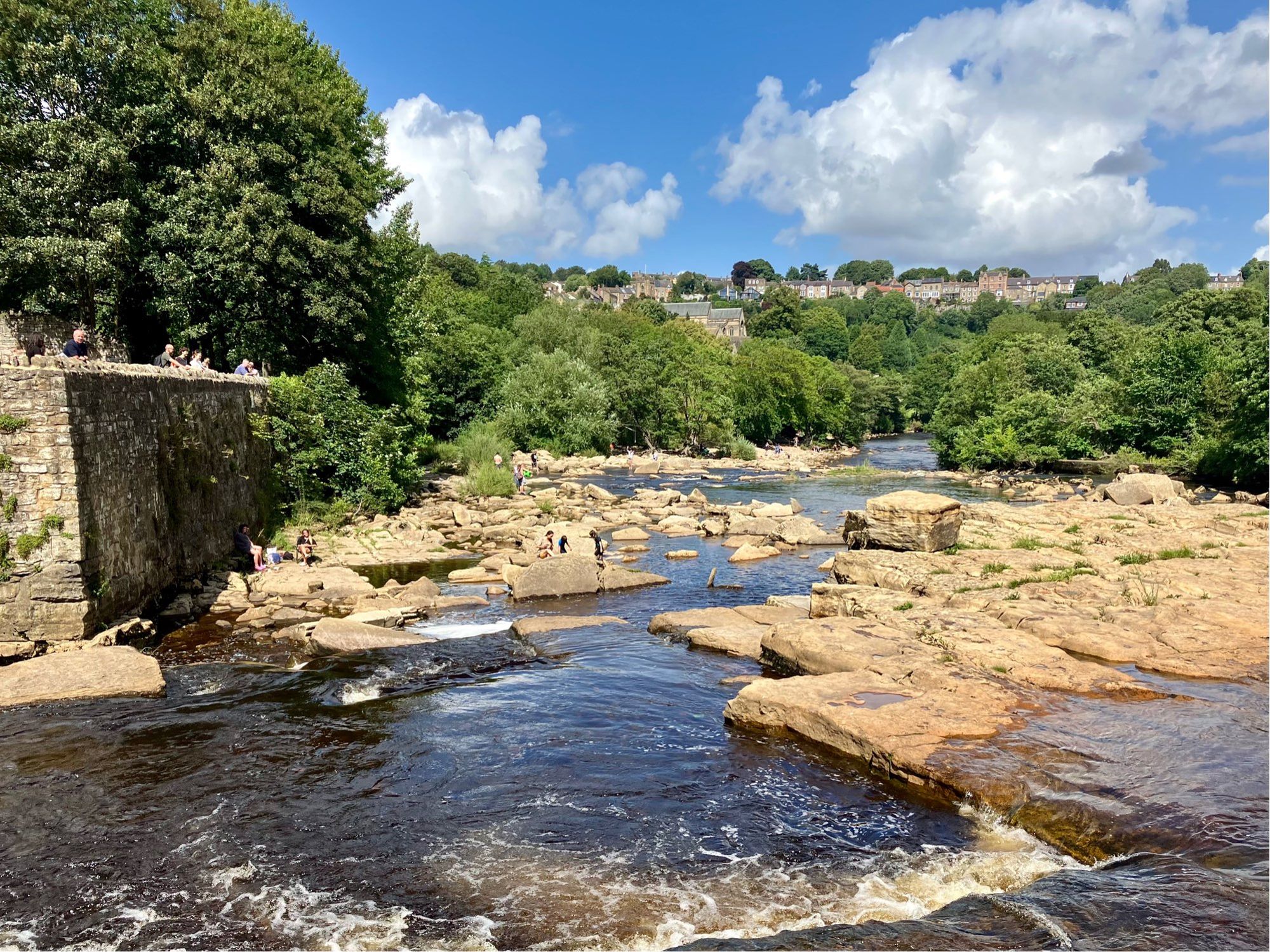 Fast flowing river Swale edged by rocks. Sunny day