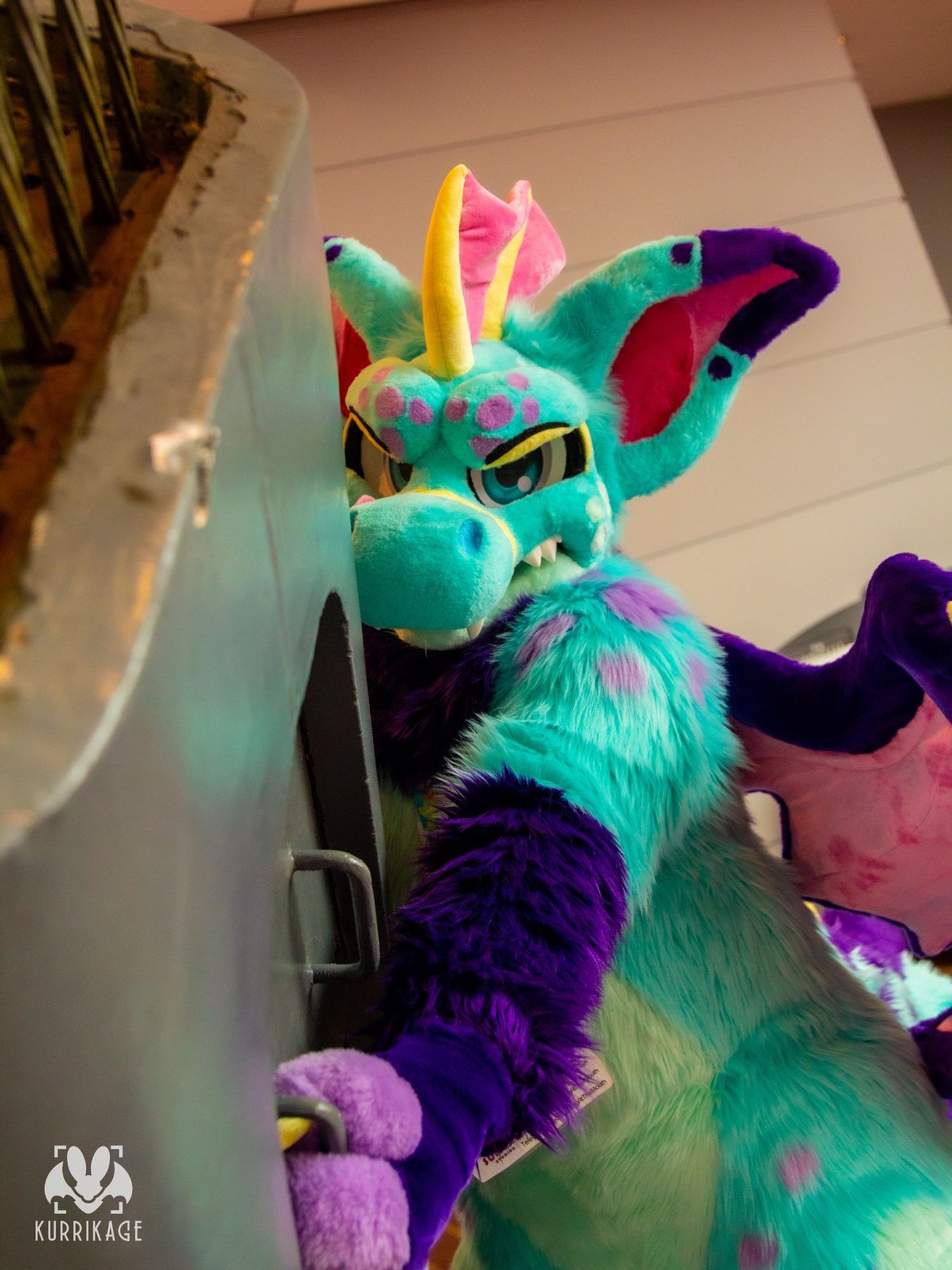 A dragon fursuit holding onto a pillar with angry looking eyes.