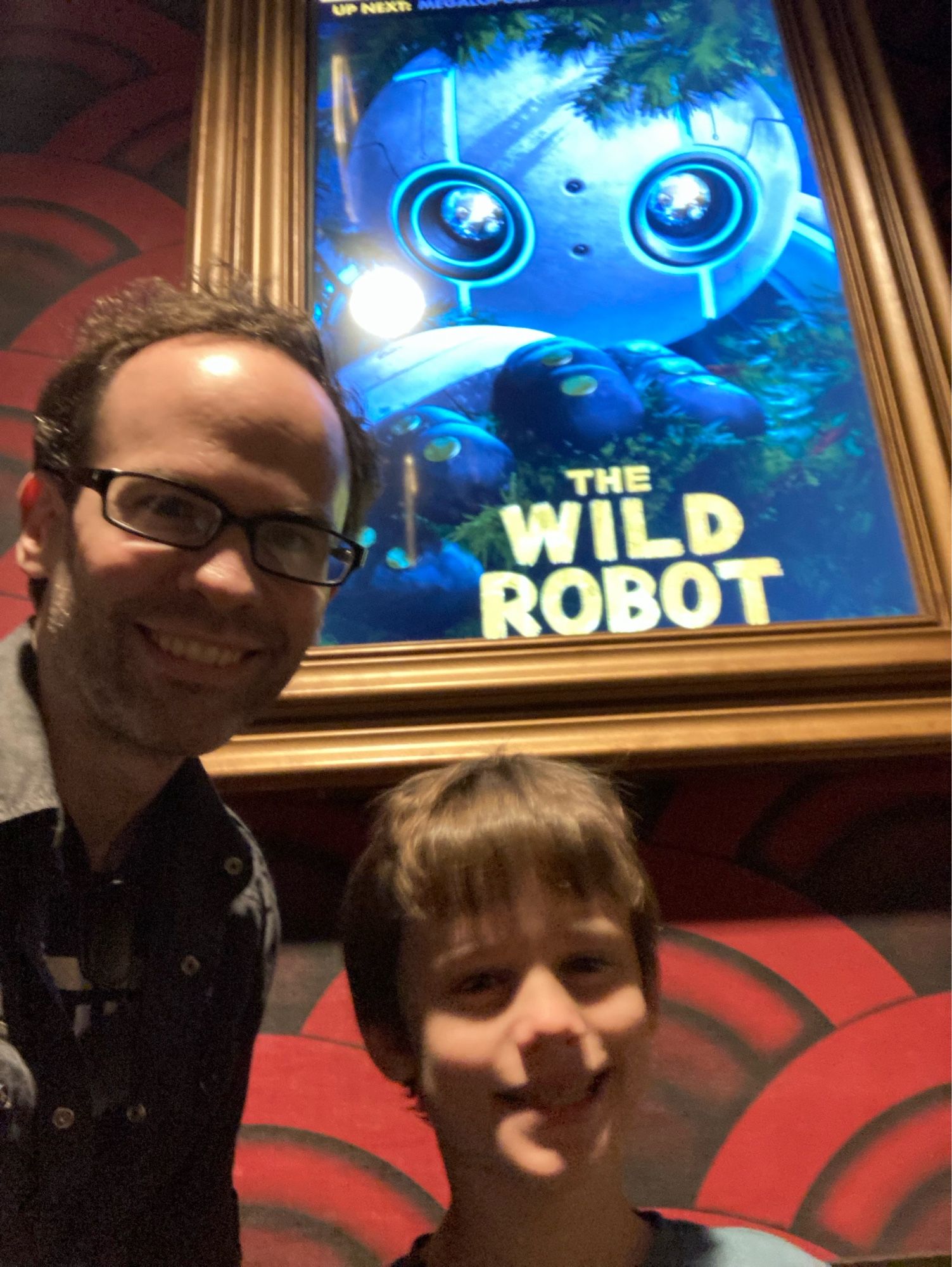 Selfie with 8yo in front of the movie poster for The Wild Robot at Alamo Drafthouse