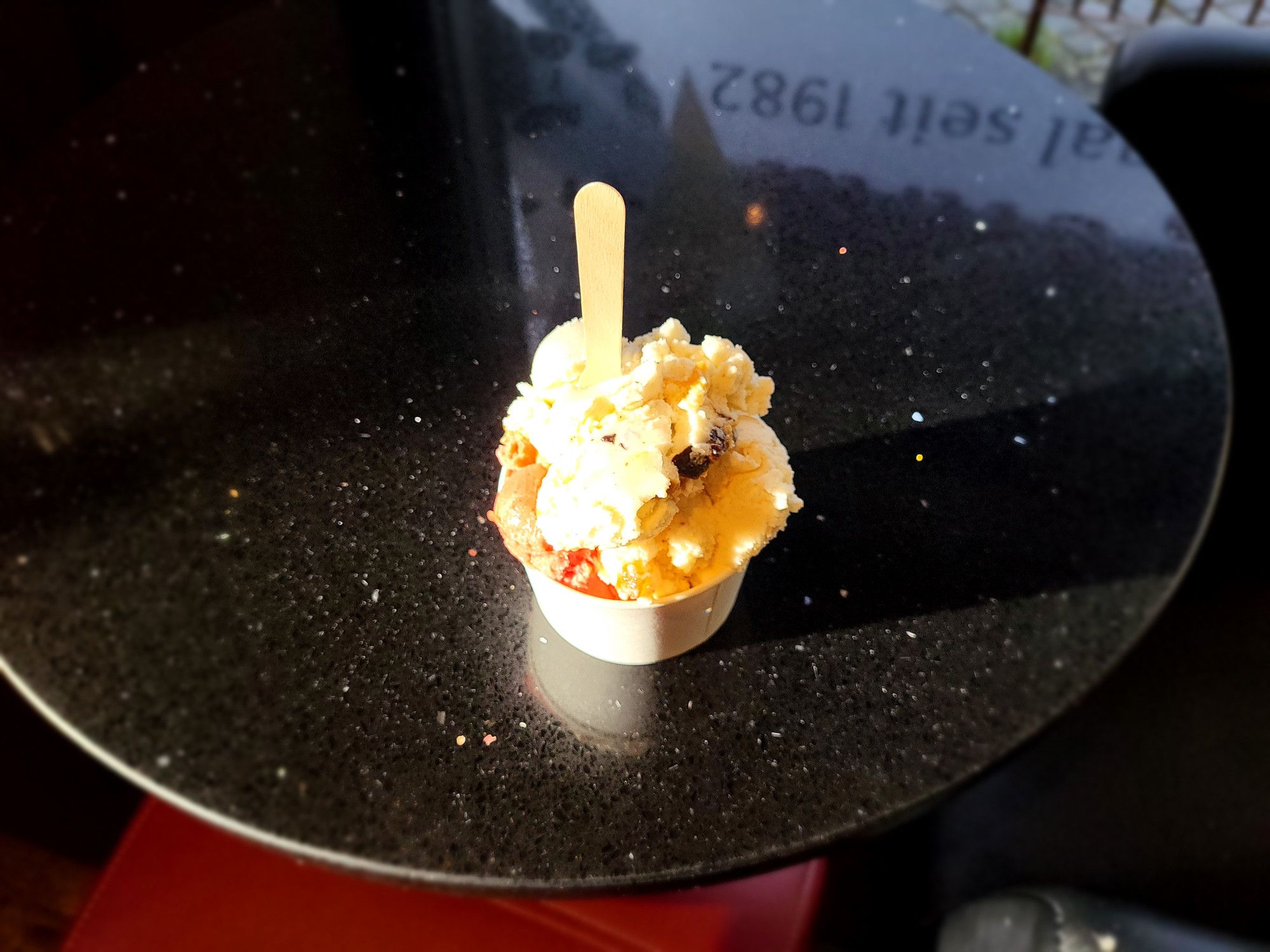 Cup of ice cream, on a table, the sun is shining on the ice cream