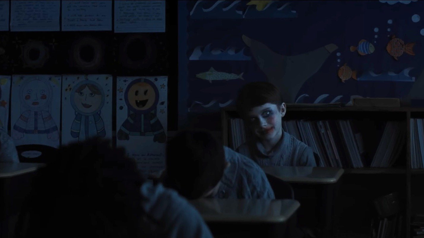 A child in creepy clown makeup in a classroom