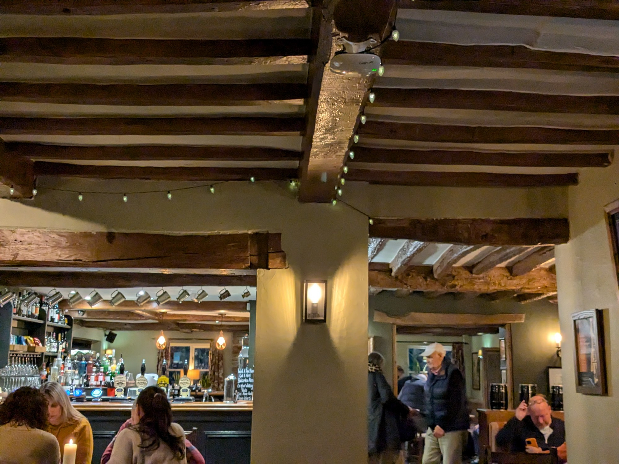 The ceilings and beams of the main bar area of the pub, illuminated by small electric lights.