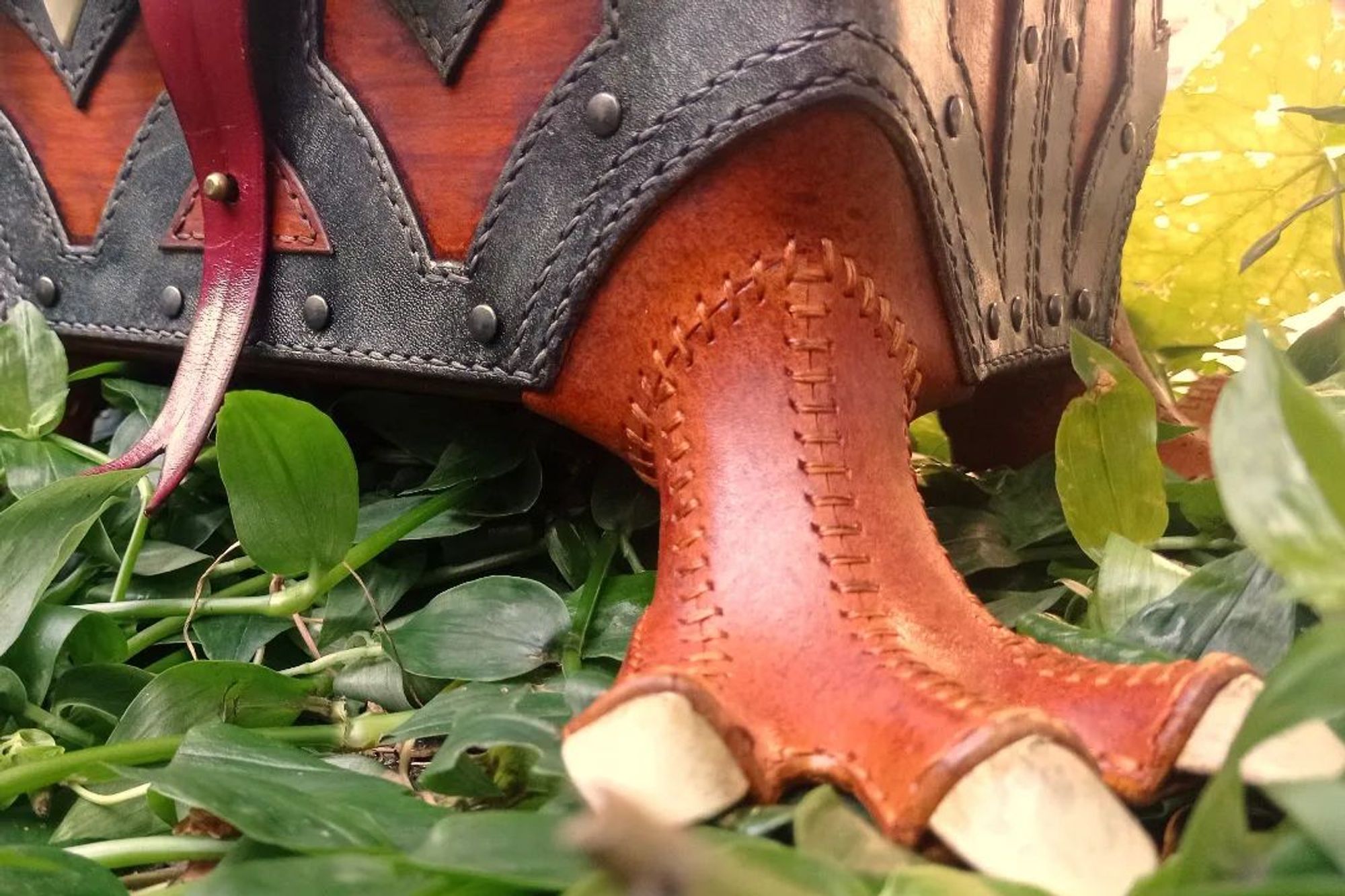 Detail pic of one of the paws, stitched with the same colour the leather and the thread, and with a grained textured, different from the wood. Also visible the low part of the front of the body and the tongue/fastener, moulded with the gap in the middle