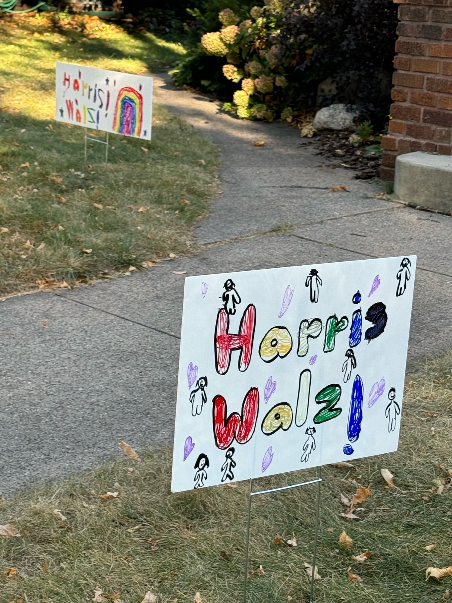 More views of child-created Harris Walz signs in a yard. These two also have hearts and rainbows