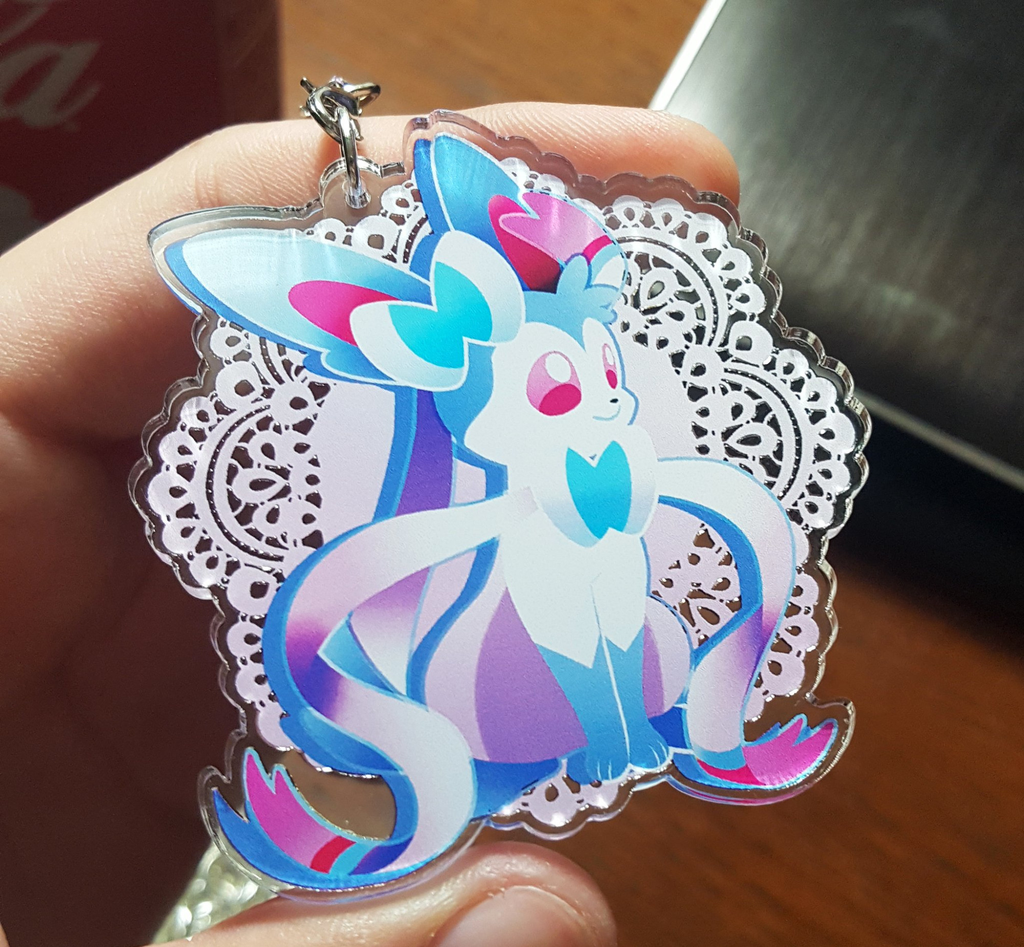 A photo of a Sylveon acrylic charm in its shiny colors.