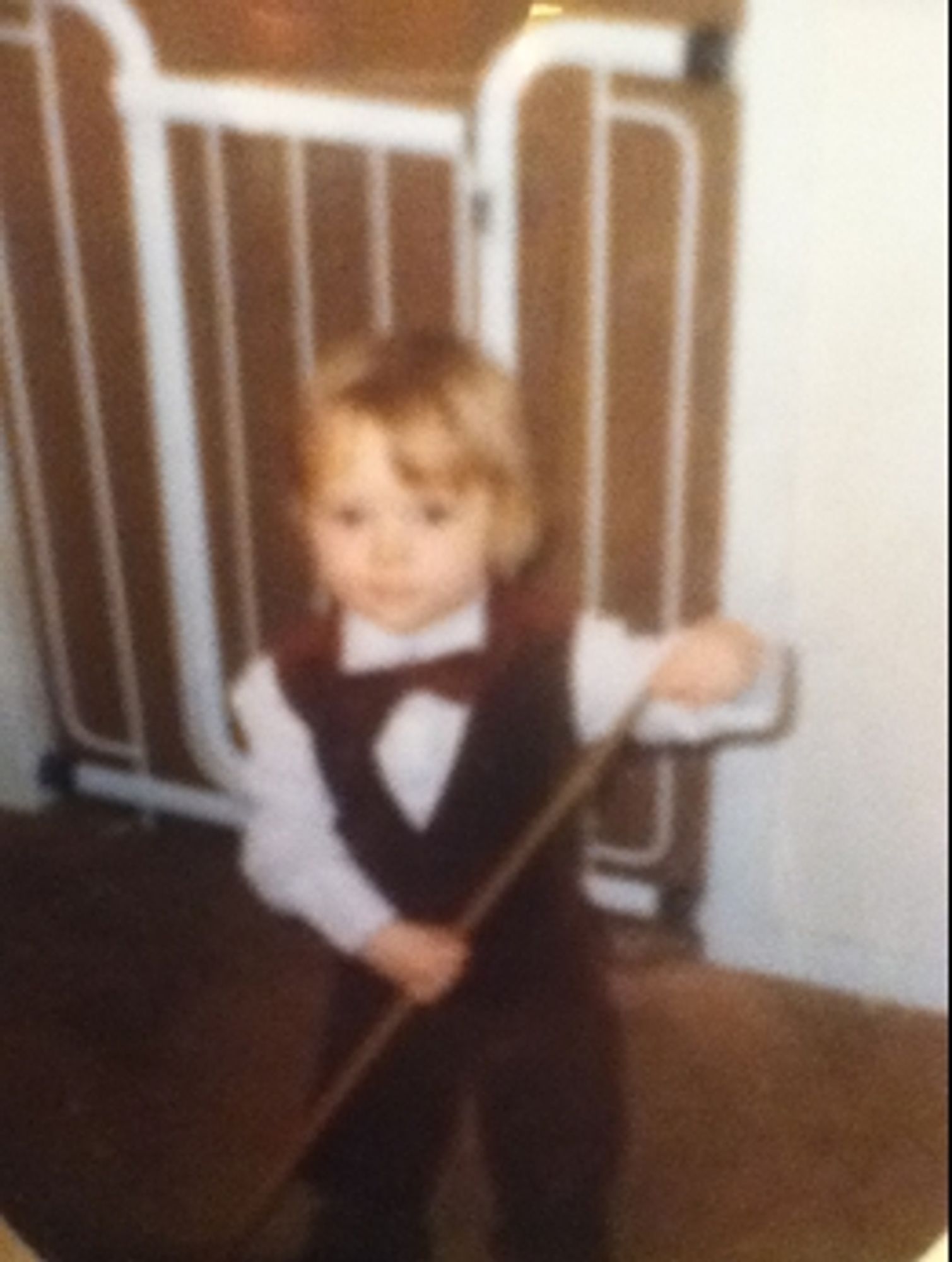 A girl with a blond mophead wearing a waistcoat and bowtie, chalking a snooker cue.