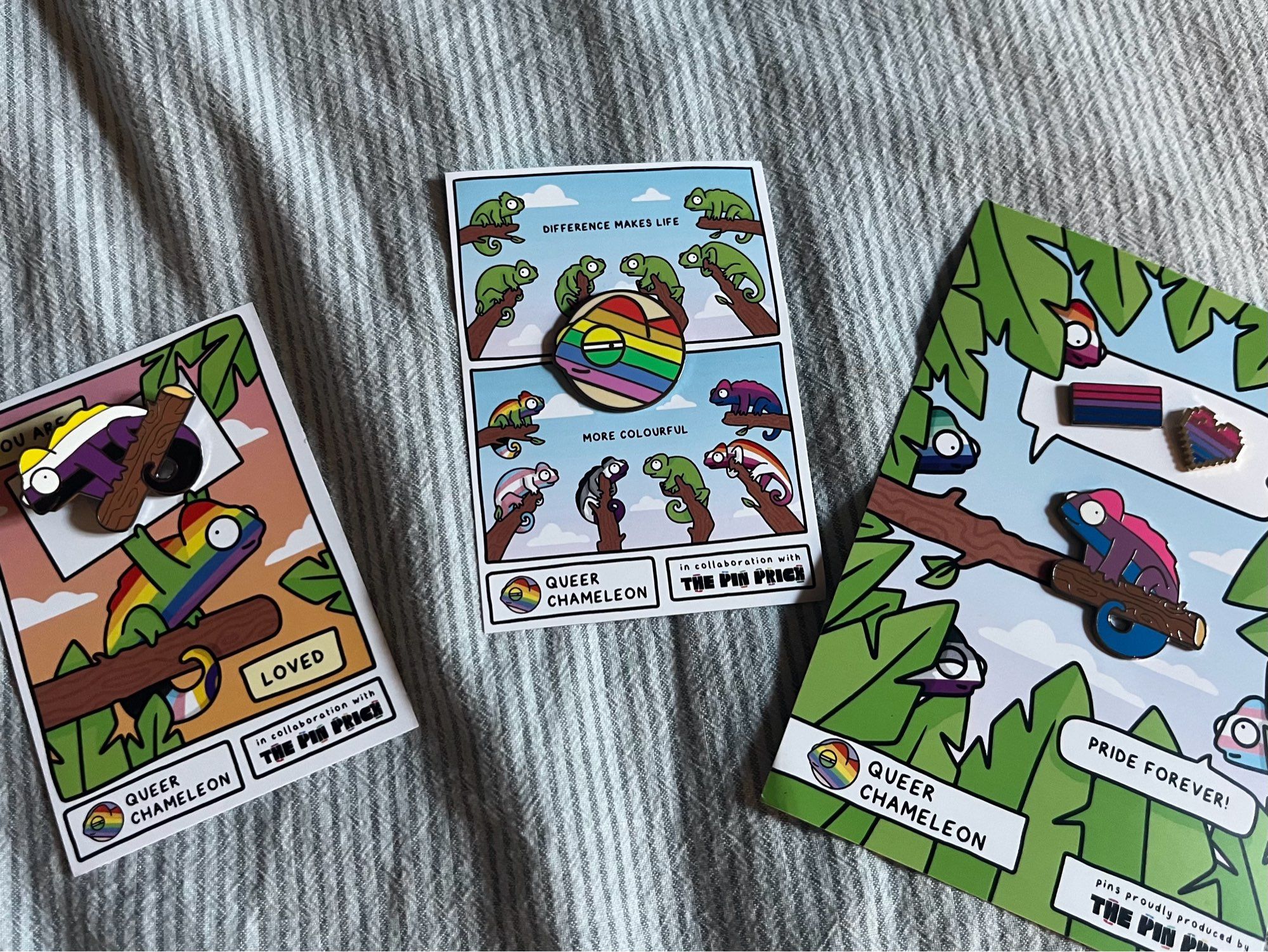 three illustrated cards with pins from queer chameleon, depicting chameleons in several pride colours