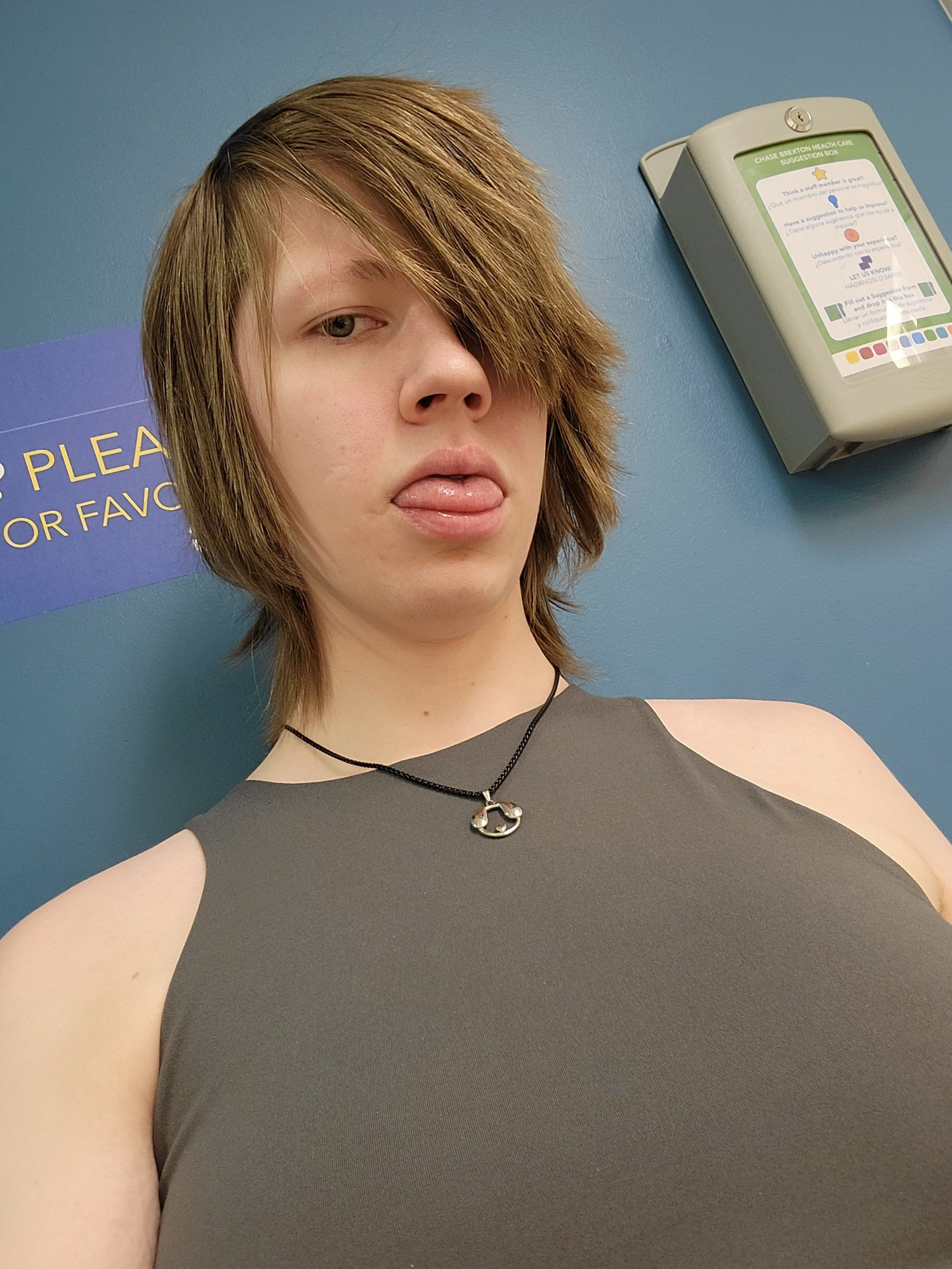 Stitch sitting in a waiting room for her HRT appointment sticking her tongue out