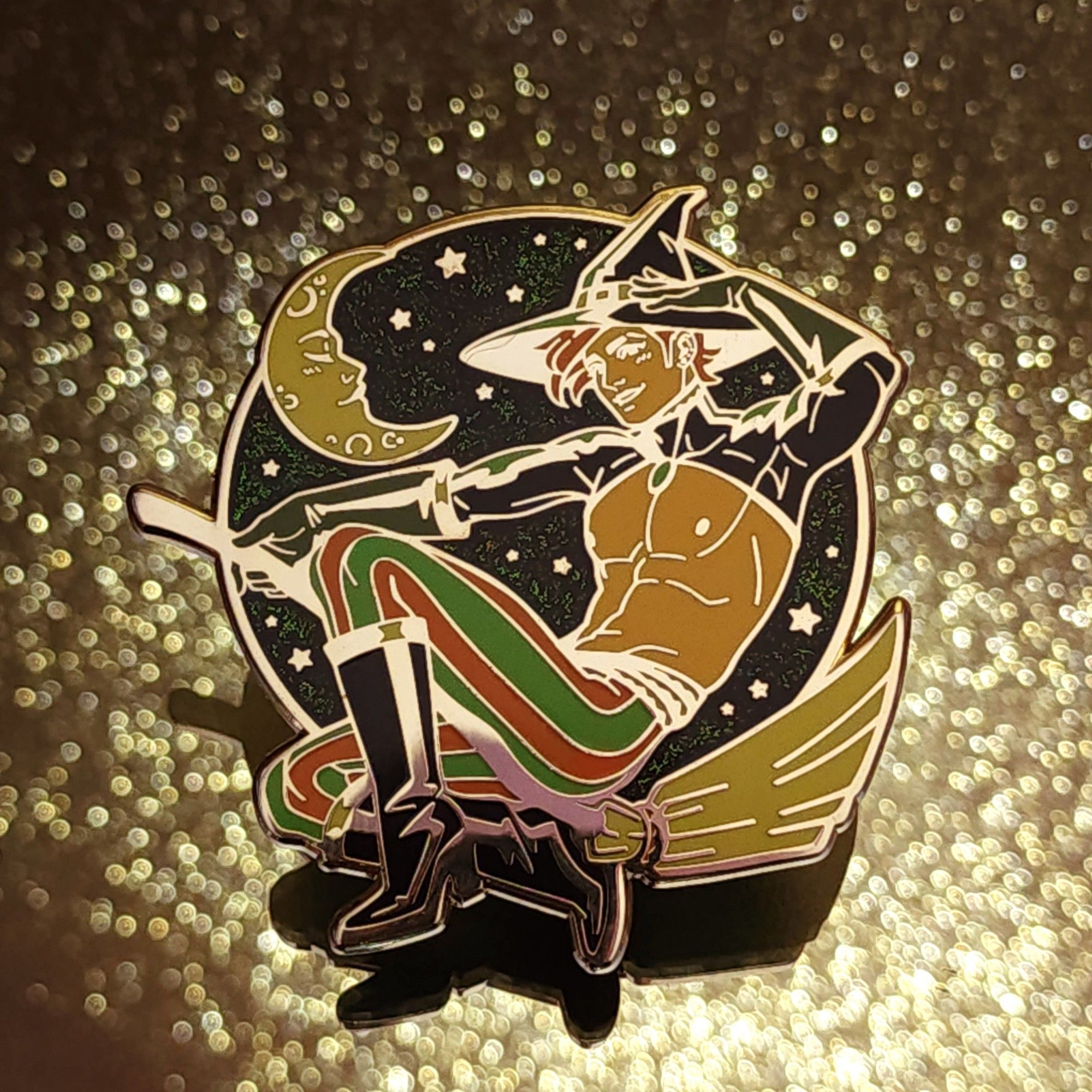 Photo of my new pin that features a handsome witch guy on a broom in front of a starry sky