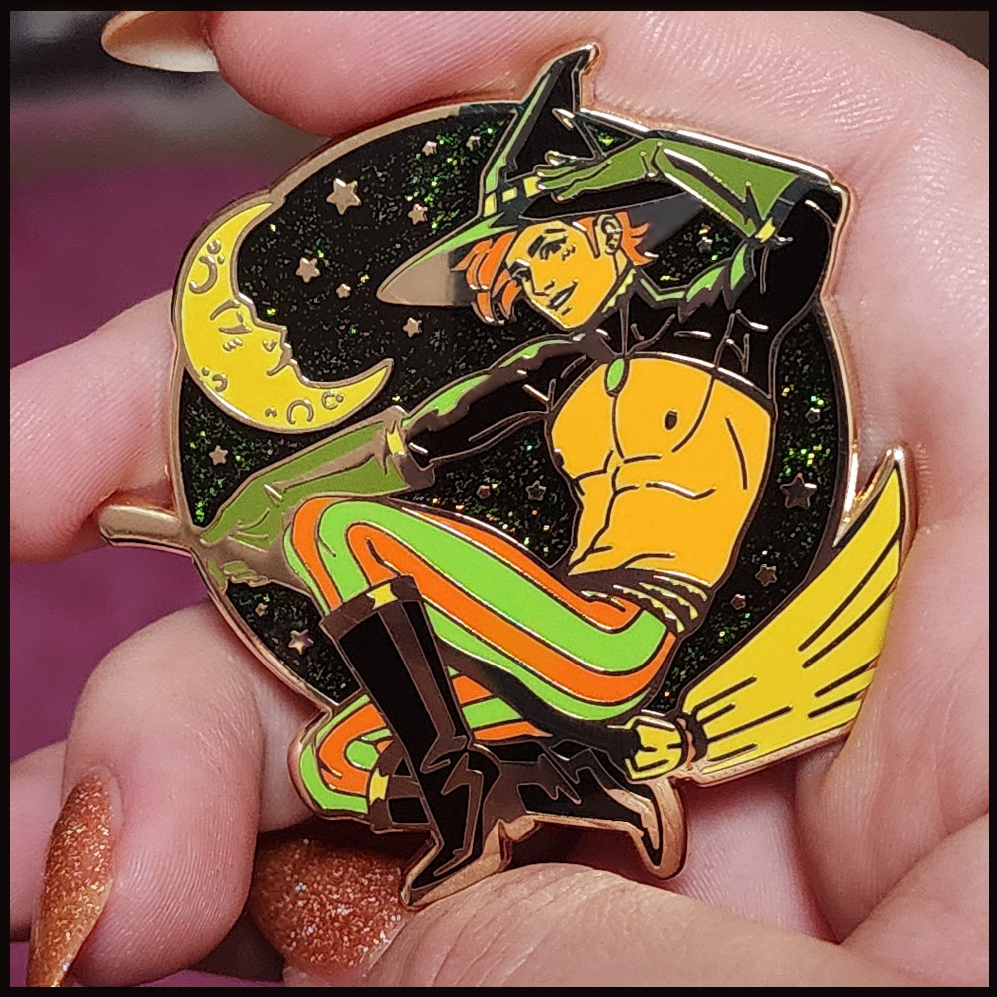 Photo of my new pin that features a handsome witch guy on a broom in front of a starry sky.