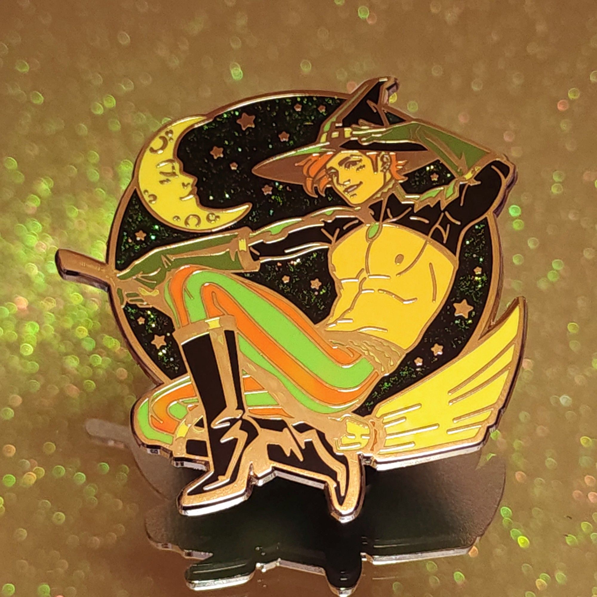 Photo of my new pin that features a handsome witch guy on a broom in front of a starry sky